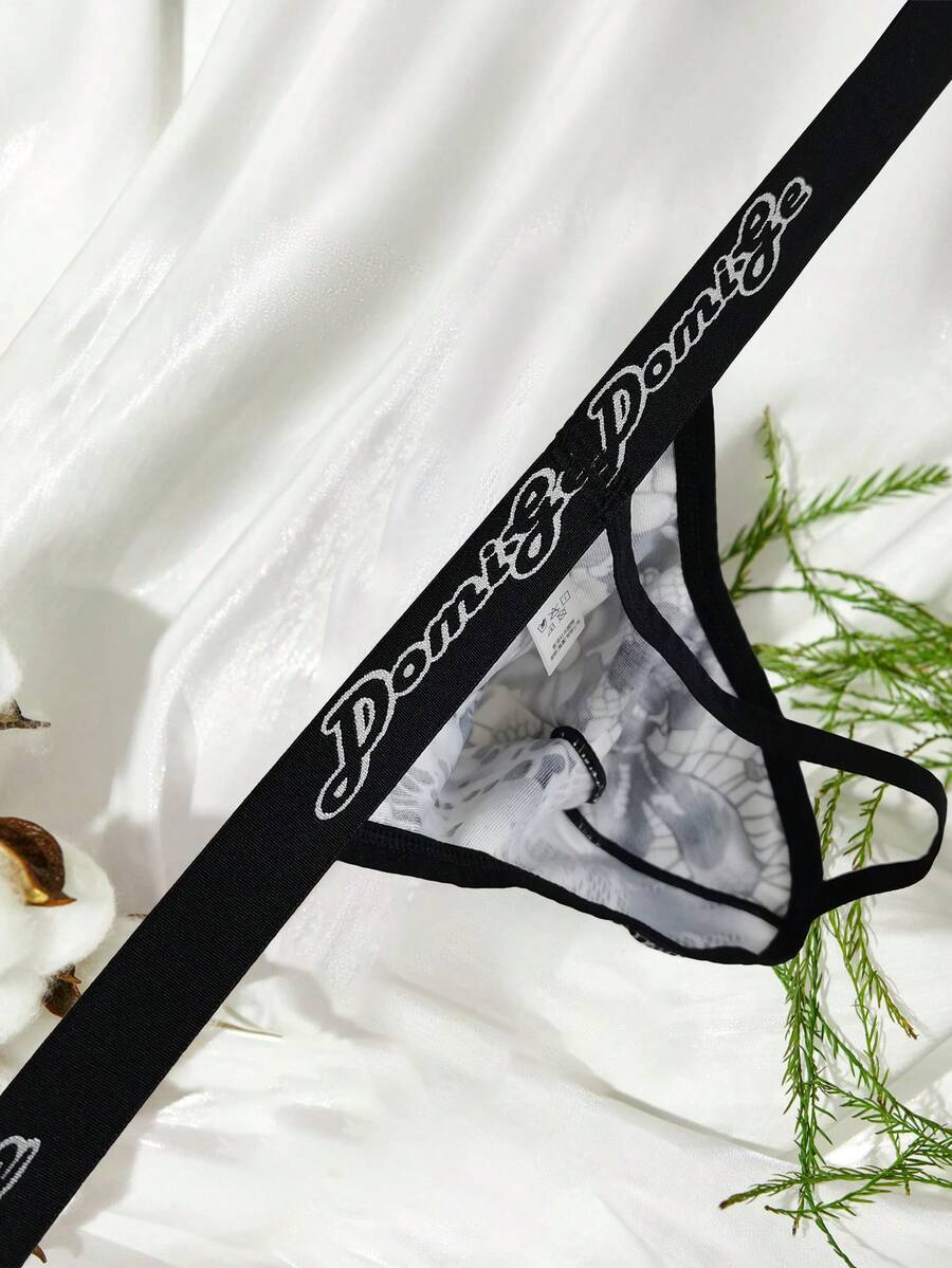 Black and white colorblock low-rise thong underwear for men featuring tape detail and knitted stretch fabric.