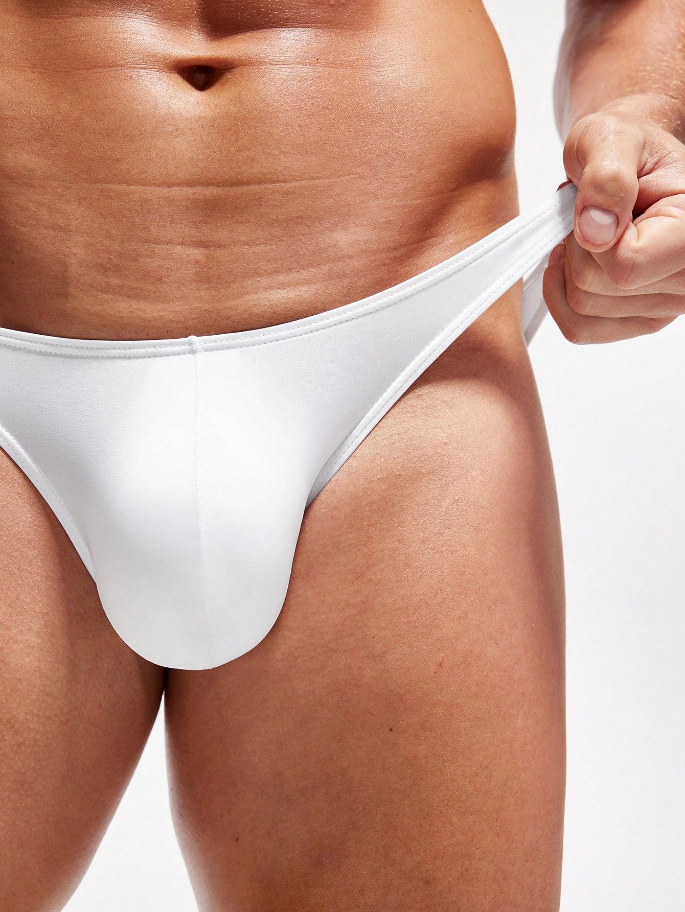 Men's white low-rise triangle briefs in semi-sheer knitted fabric with colorblock detail and medium stretch.
