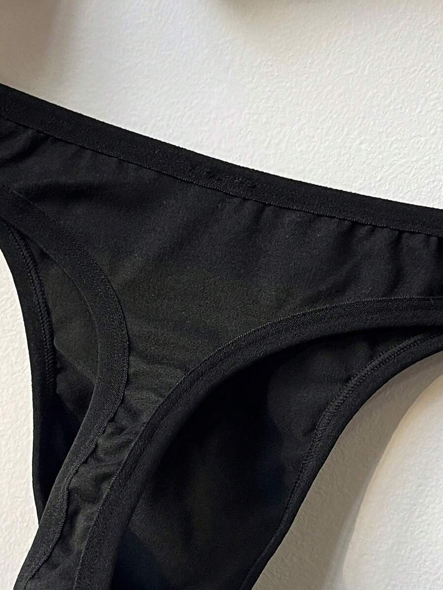 Black low-rise men's thong underwear with letter print pattern made of knitted fabric.