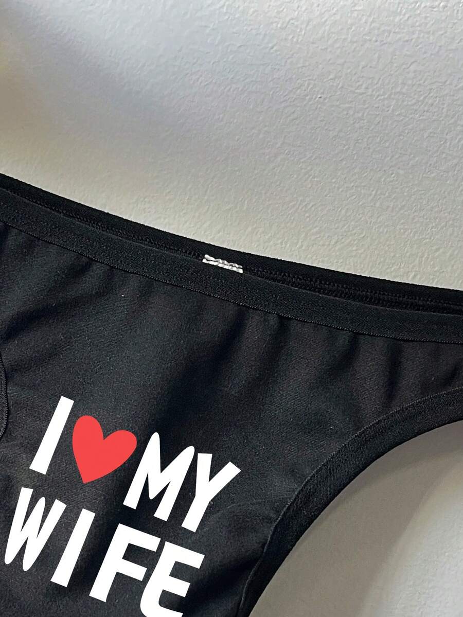 Black low-rise men's thong underwear with letter print pattern made of knitted fabric.