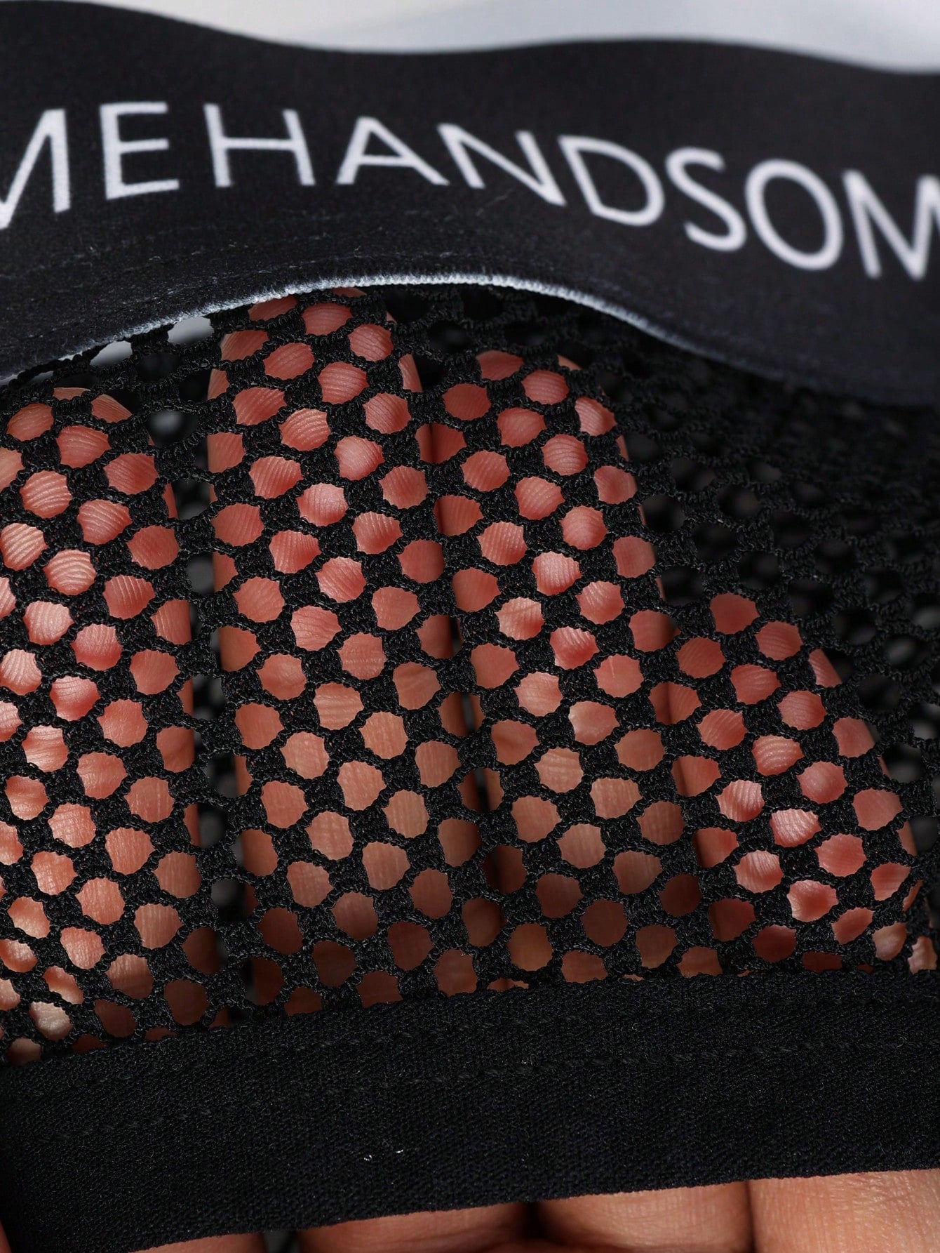 Black men's low rise briefs with cut out detail, letter elastic waistband, and medium-stretch knitted polyamide blend.