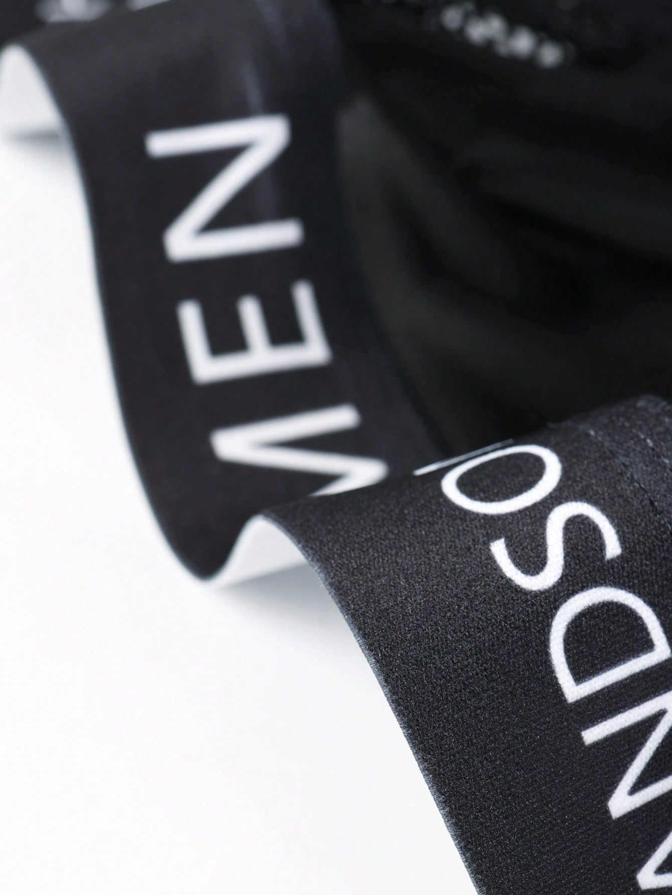 Black men's low rise briefs with cut out detail, letter elastic waistband, and medium-stretch knitted polyamide blend.