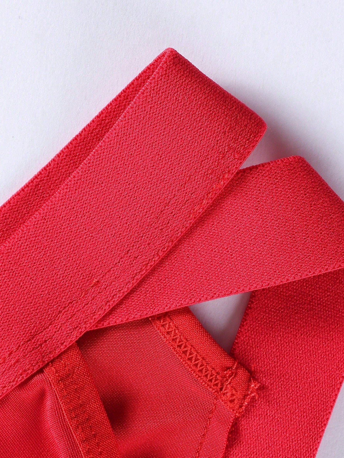 Red men's low rise thong underwear with lace panel, cut-out detail, and medium stretch knitted fabric.