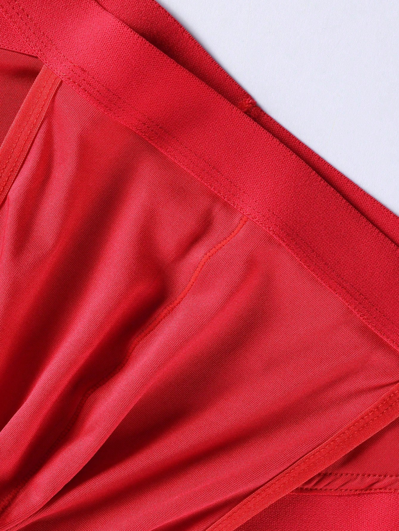 Red men's low rise thong underwear with lace panel, cut-out detail, and medium stretch knitted fabric.