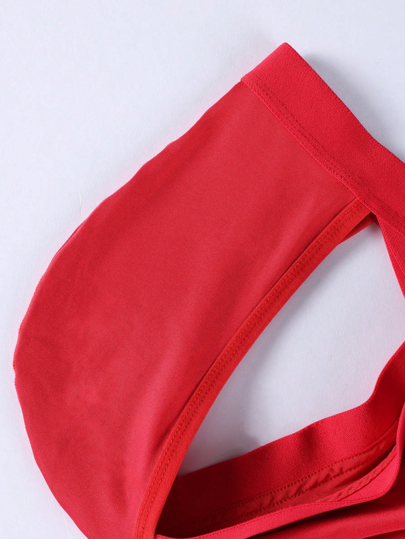 Red men's low rise thong underwear with lace panel, cut-out detail, and medium stretch knitted fabric.