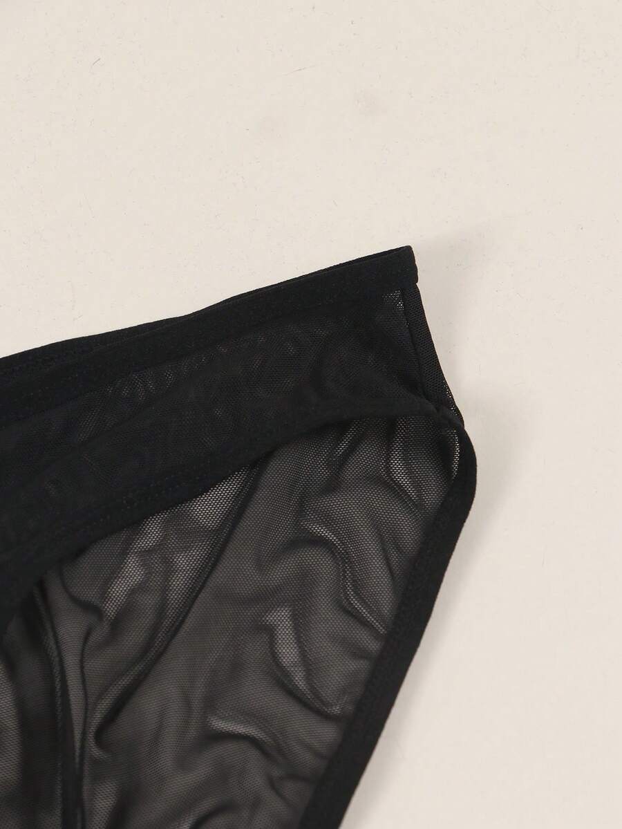 Black semi-sheer mesh thong underwear for men featuring a heart eye print pattern and low-rise fit.