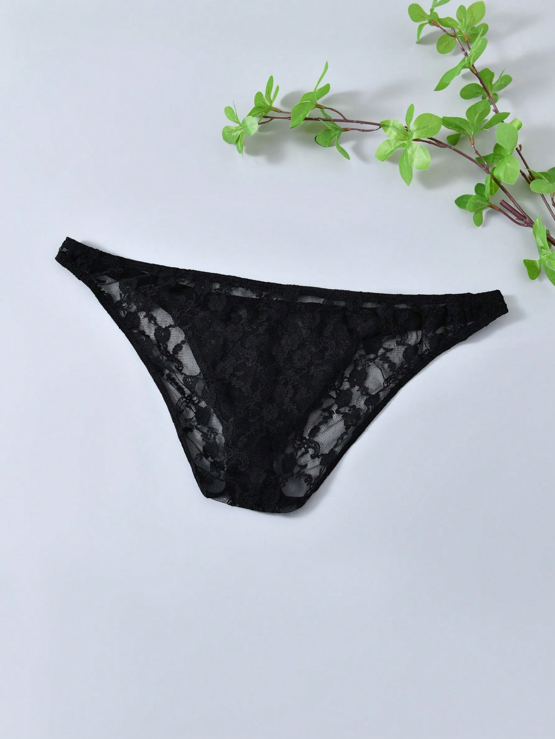 Men's black lace thong underwear with low rise fit, contrast lace detail, and T-back design in medium-stretch polyester elastane fabric.