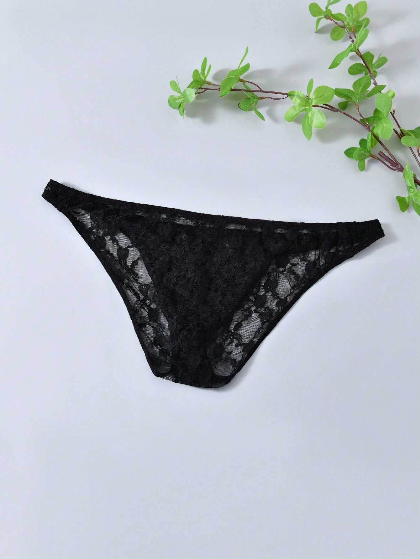 Men's black lace thong underwear with low rise fit, contrast lace detail, and T-back design in medium-stretch polyester elastane fabric.