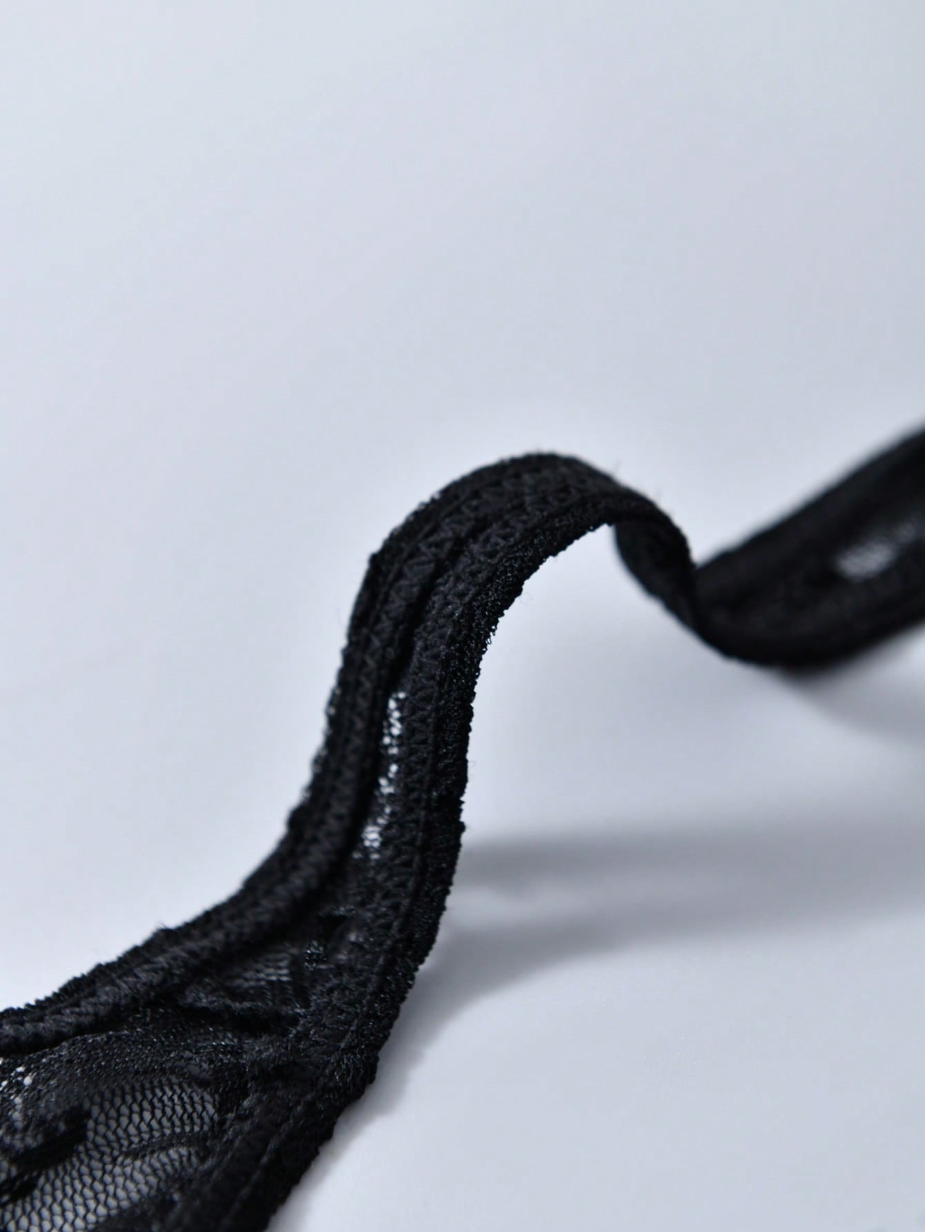 Men's black lace thong underwear with low rise fit, contrast lace detail, and T-back design in medium-stretch polyester elastane fabric.