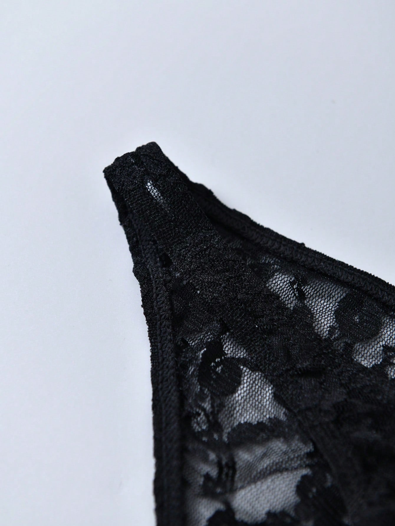 Men's black lace thong underwear with low rise fit, contrast lace detail, and T-back design in medium-stretch polyester elastane fabric.