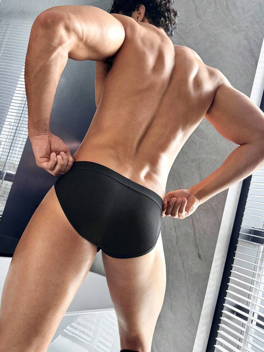 Men's black low-rise thong underwear with a ring-connected hollow design in knitted stretch fabric.