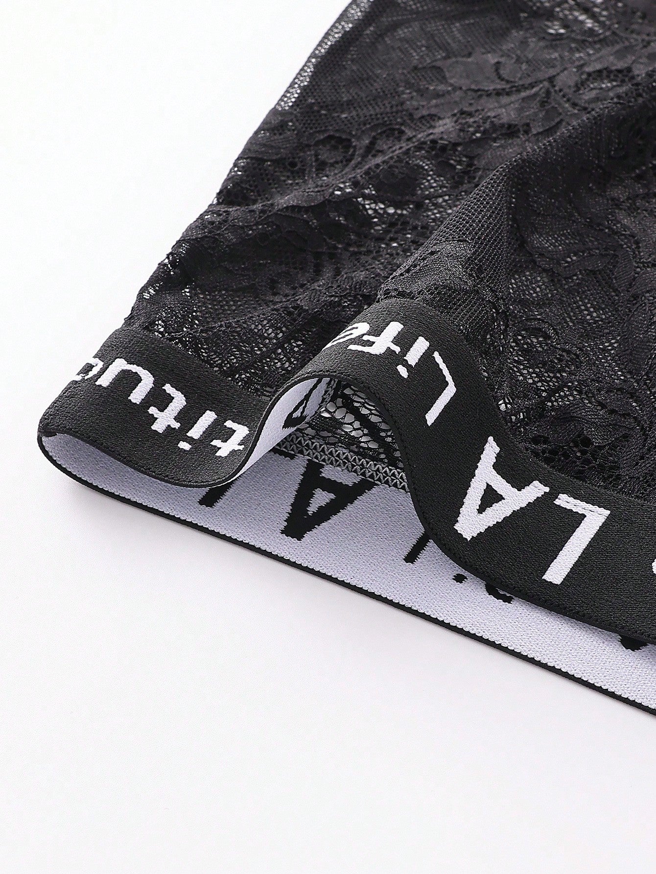 Men's black low rise lace briefs with letter waistband, semi-sheer fabric and medium stretch design.