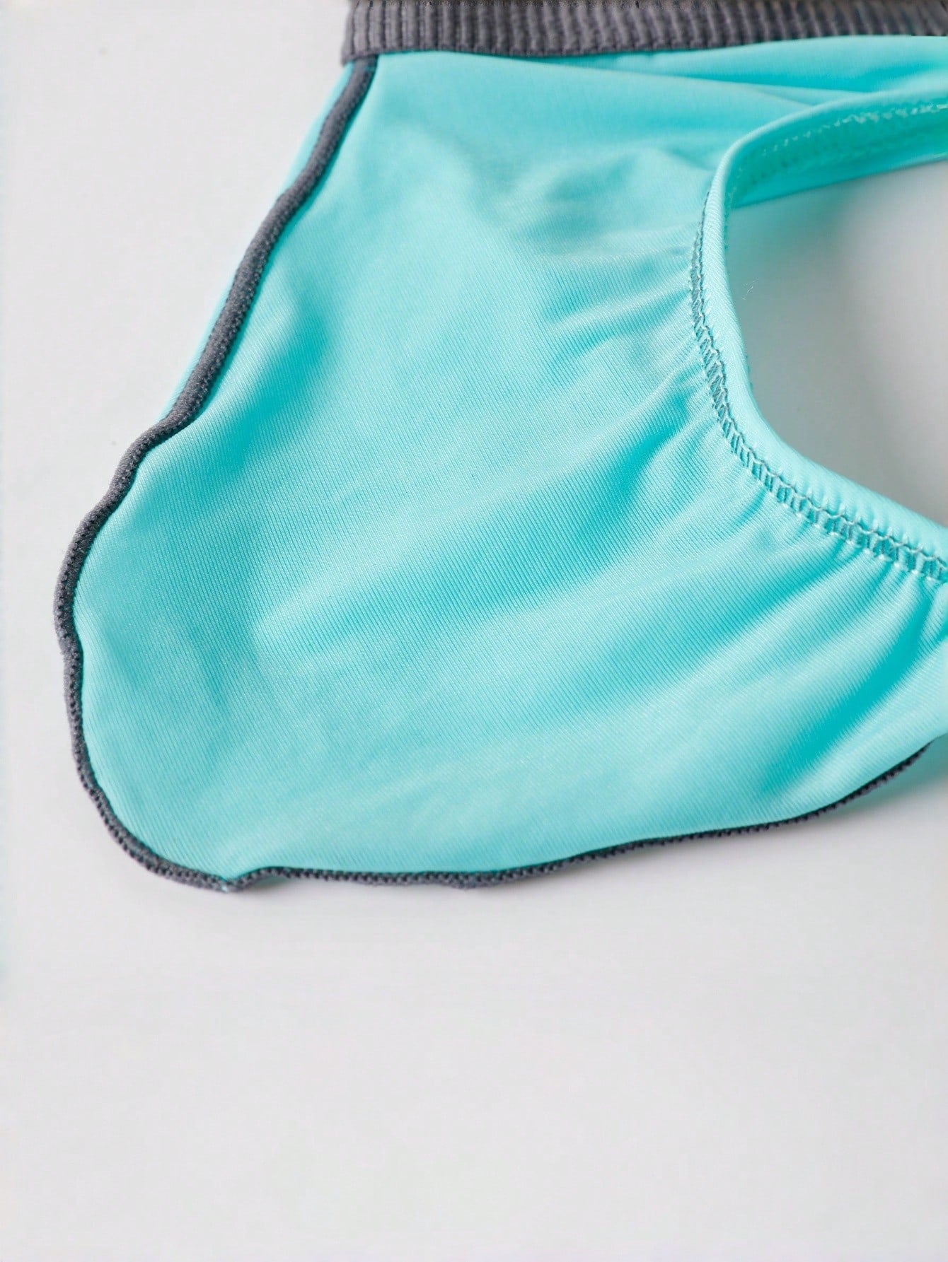 Blue men's thong underwear with contrast binding and a low-rise design in medium-stretch polyamide elastane fabric.
