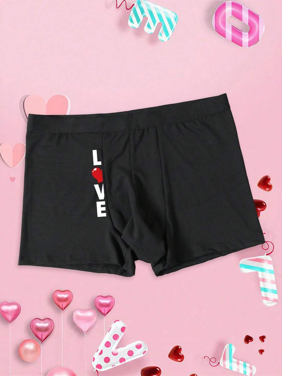 Black men's elephant pouch boxer shorts featuring letter print design and high-stretch fabric.