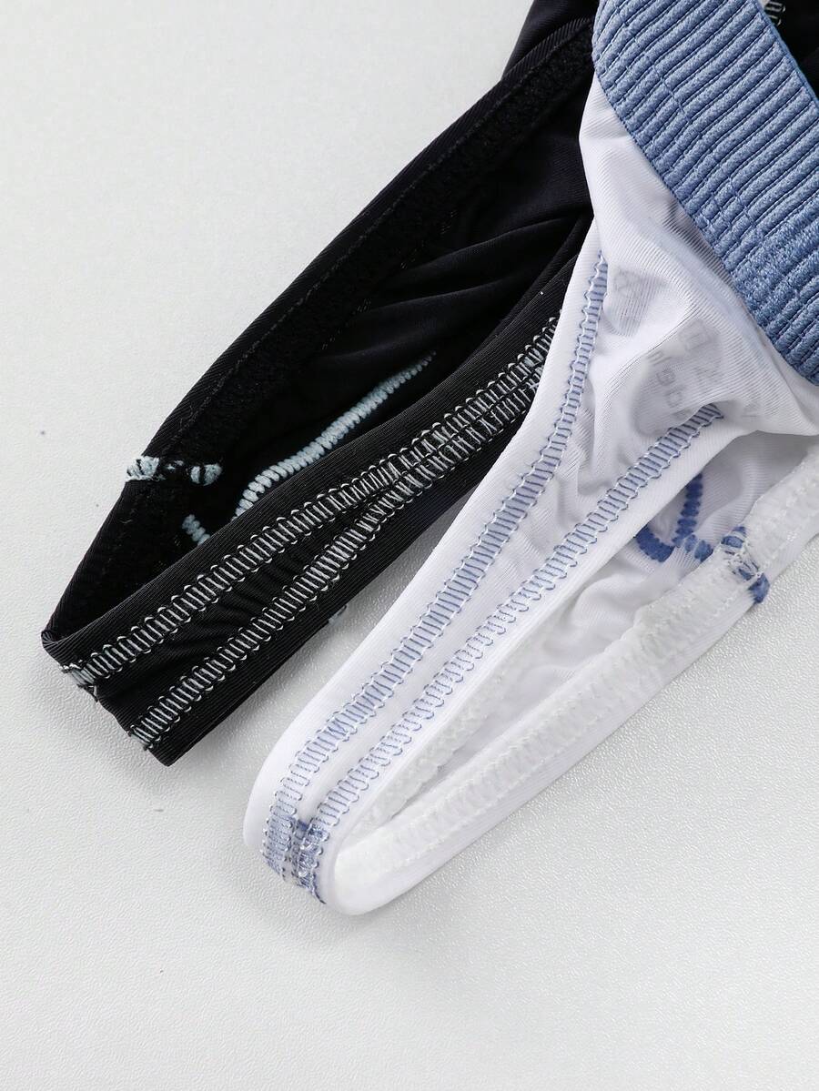 Set of two men's low-rise thong underwear featuring multicolor plant print and contrast waistband.