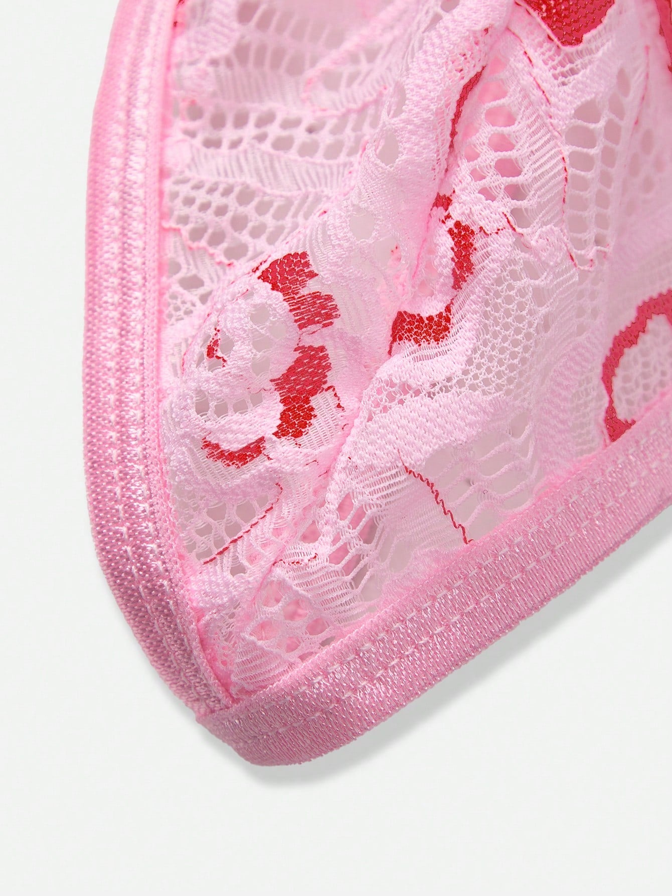 Pink men's lace thong underwear with geometric and floral-inspired print, low-rise waist, unlined design, and medium-stretch fabric.