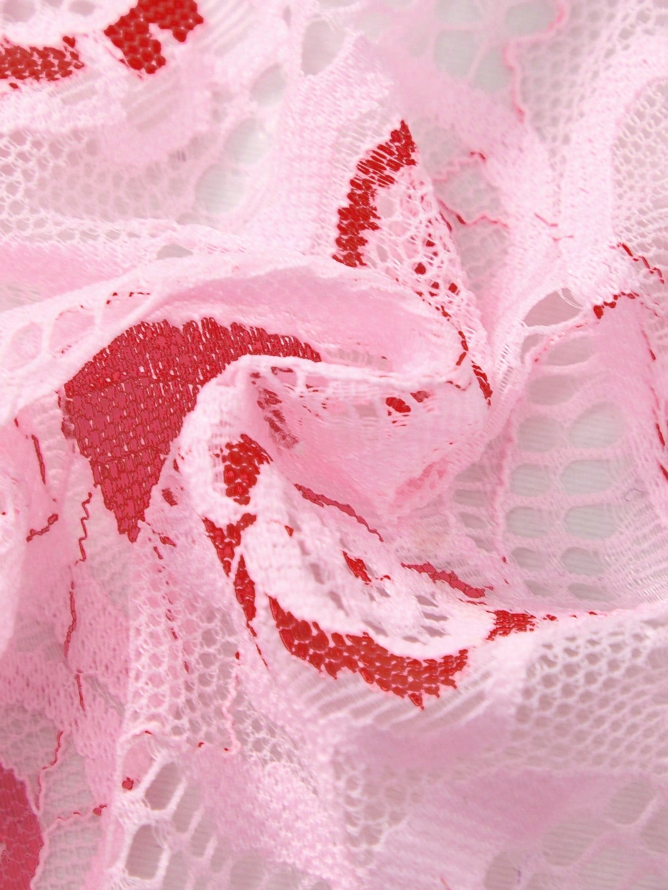 Pink men's lace thong underwear with geometric and floral-inspired print, low-rise waist, unlined design, and medium-stretch fabric.