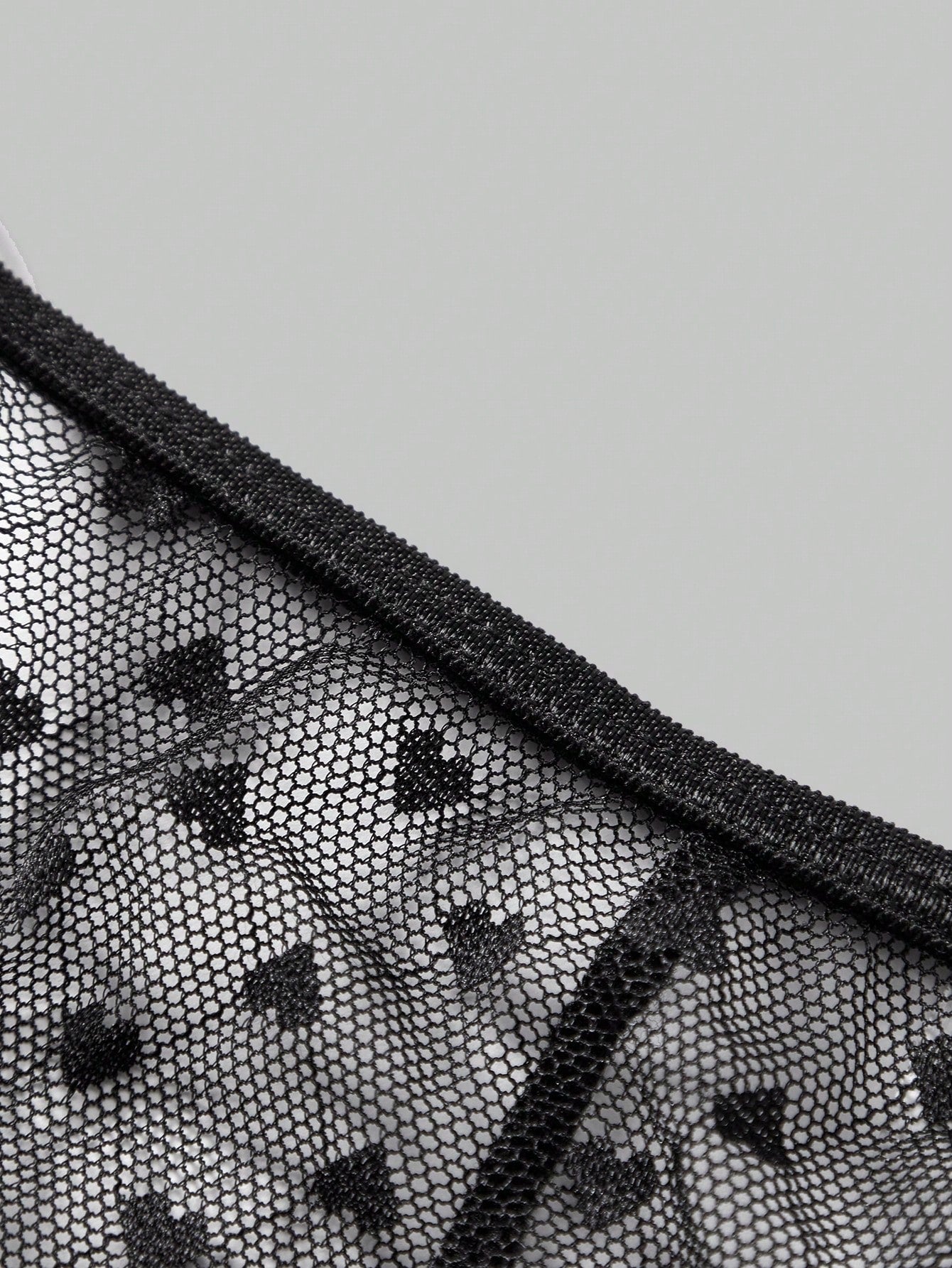 Men's black sheer mesh thong underwear with geometric pattern, low rise fit, hollow out detail, and ring accent.