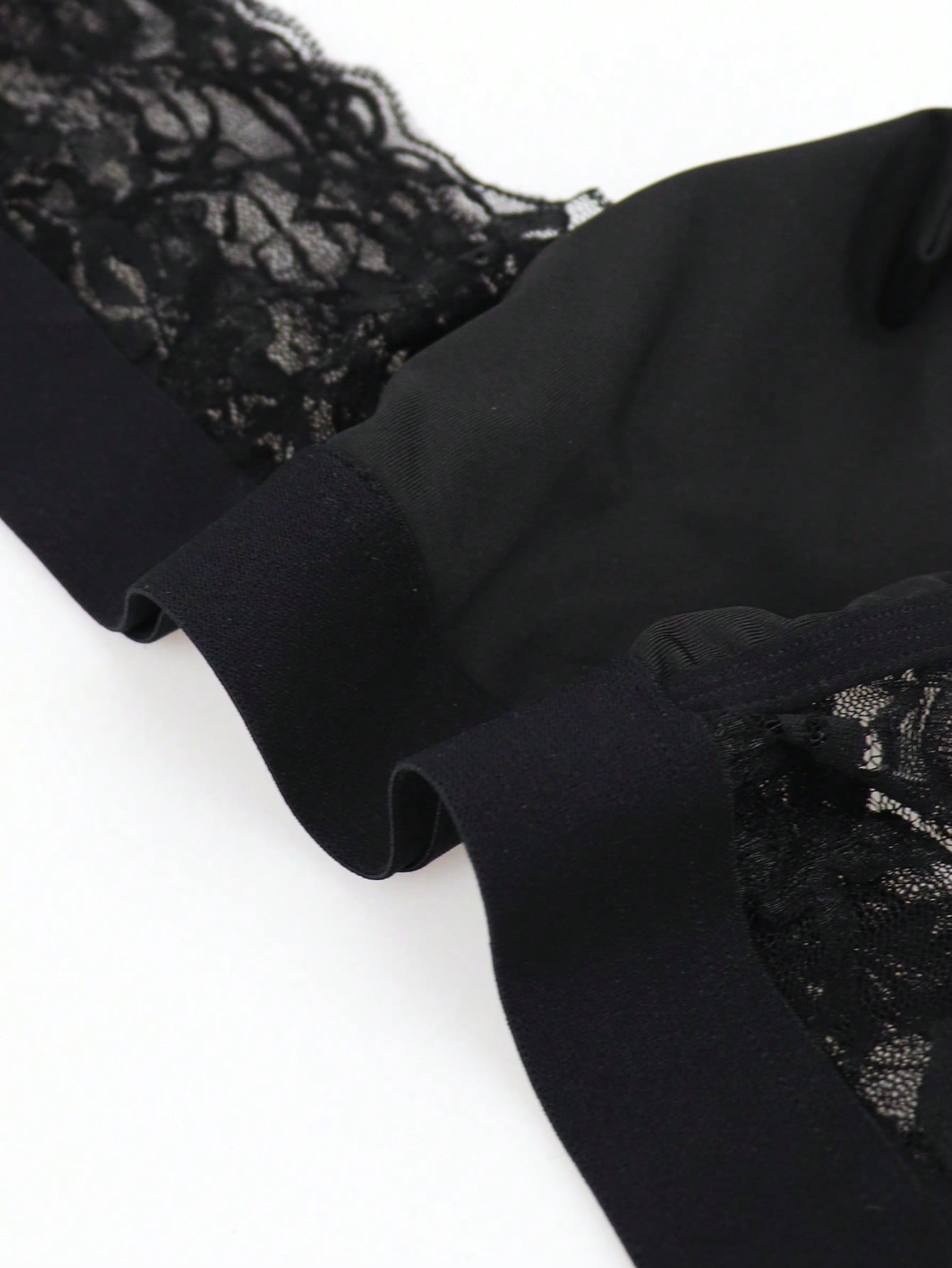 Men's black mid-rise thong briefs in knitted polyamide elastane fabric with medium stretch and plant pattern.