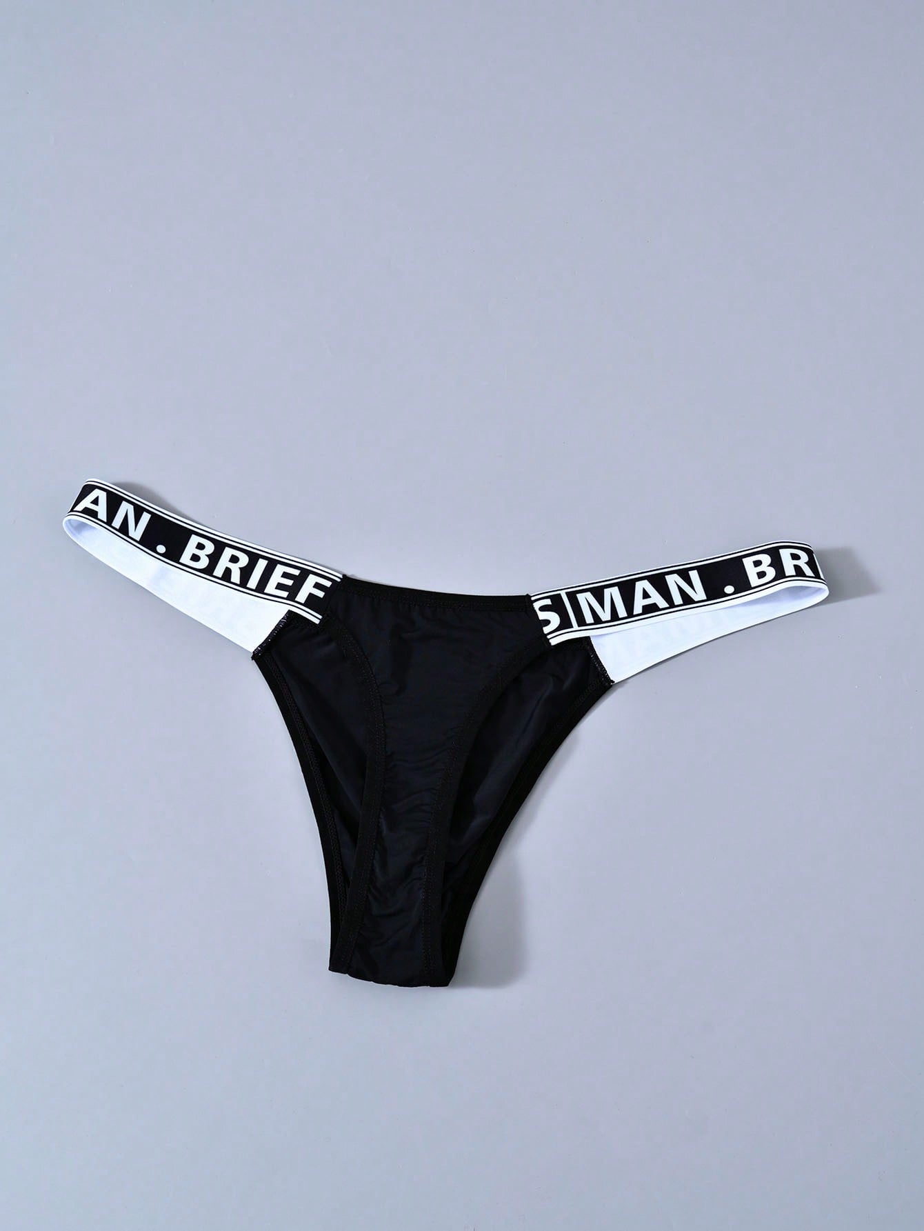 Men's mid rise thong underwear with textured pattern and letter-style tape waistband, made from polyester elastane stretch fabric.