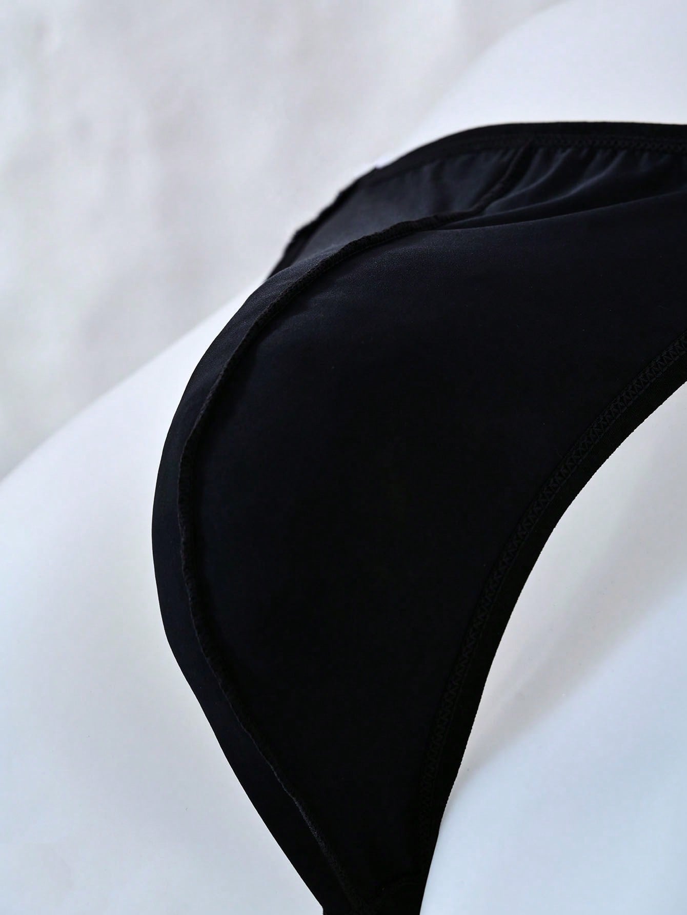 Men's mid rise thong underwear with textured pattern and letter-style tape waistband, made from polyester elastane stretch fabric.