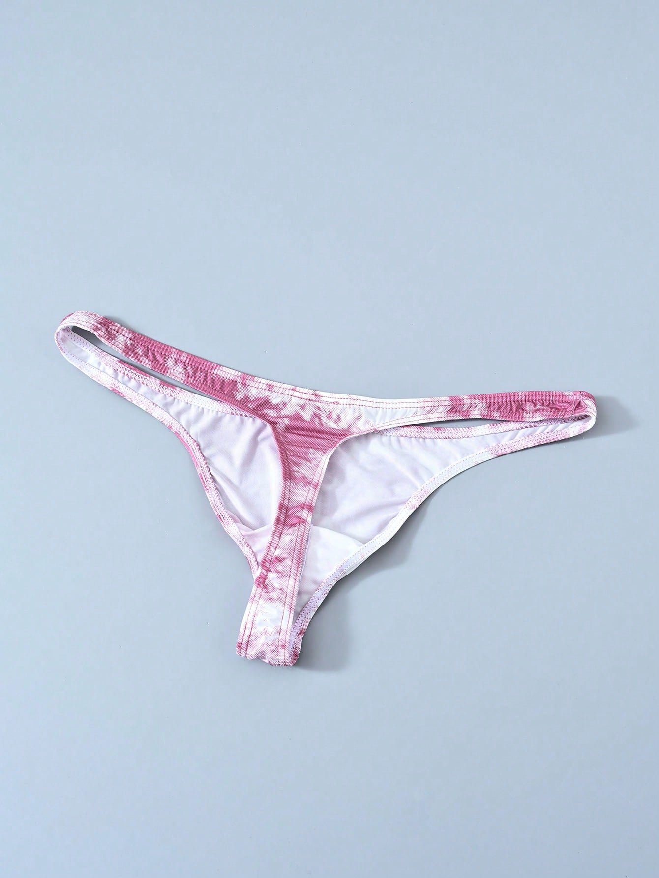 Men's tie dye thong underwear with a low rise fit and T-back design, made from polyester and elastane stretch fabric.