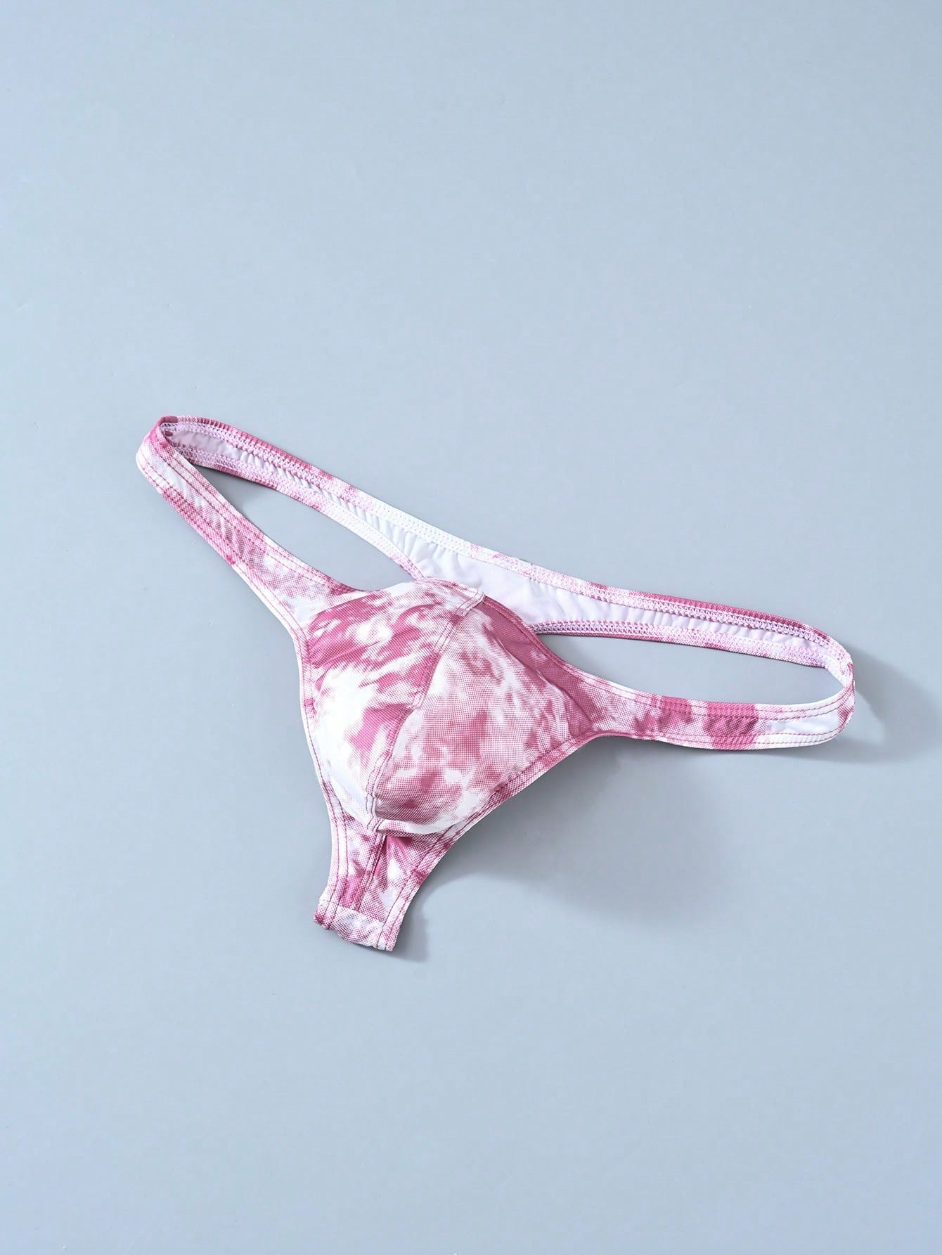 Men's tie dye thong underwear with a low rise fit and T-back design, made from polyester and elastane stretch fabric.