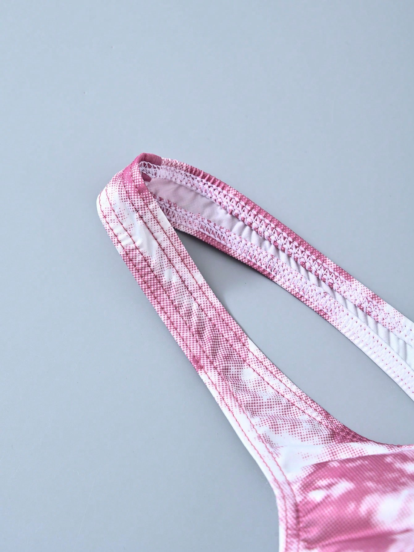 Men's tie dye thong underwear with a low rise fit and T-back design, made from polyester and elastane stretch fabric.