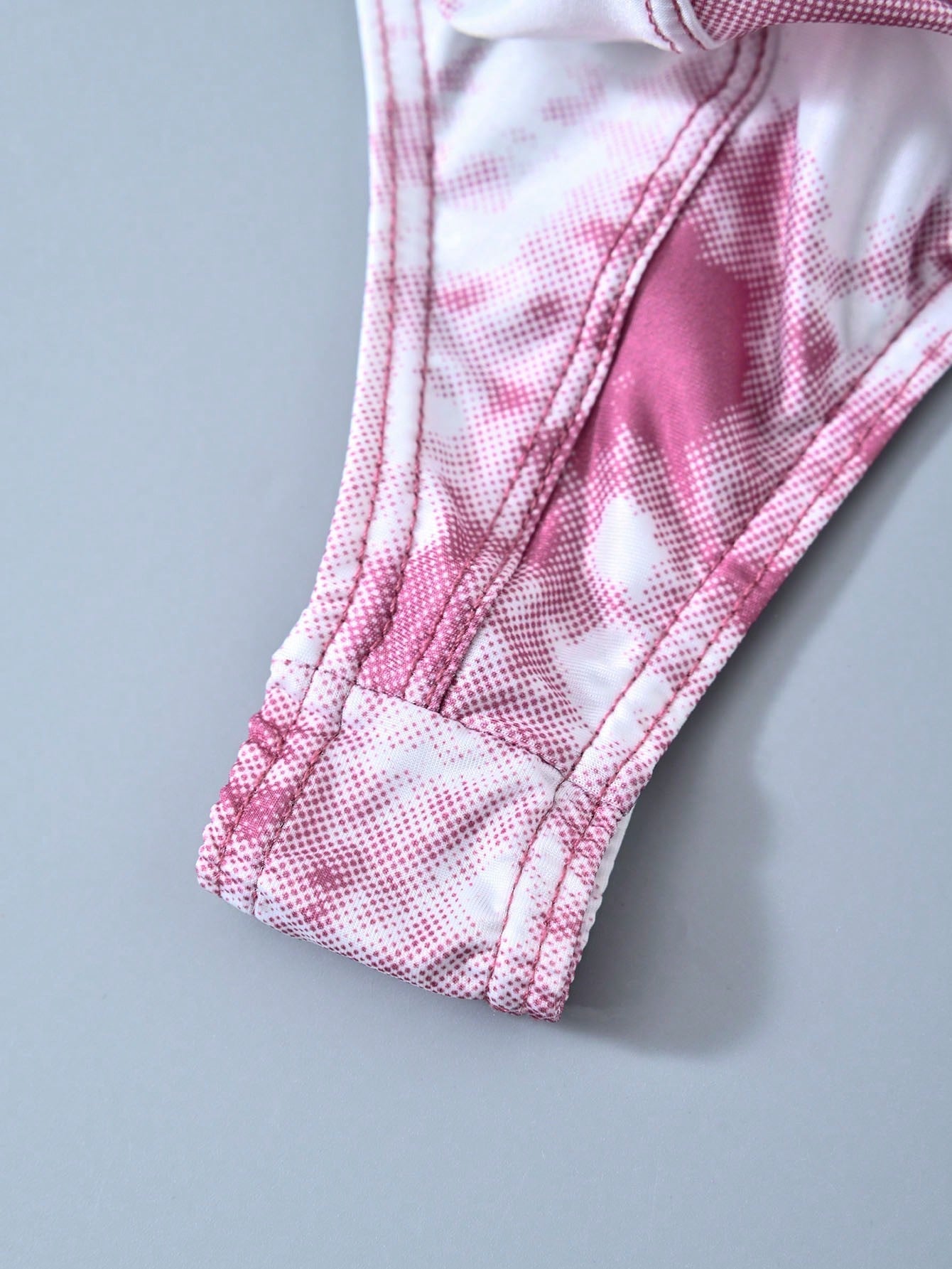 Men's tie dye thong underwear with a low rise fit and T-back design, made from polyester and elastane stretch fabric.