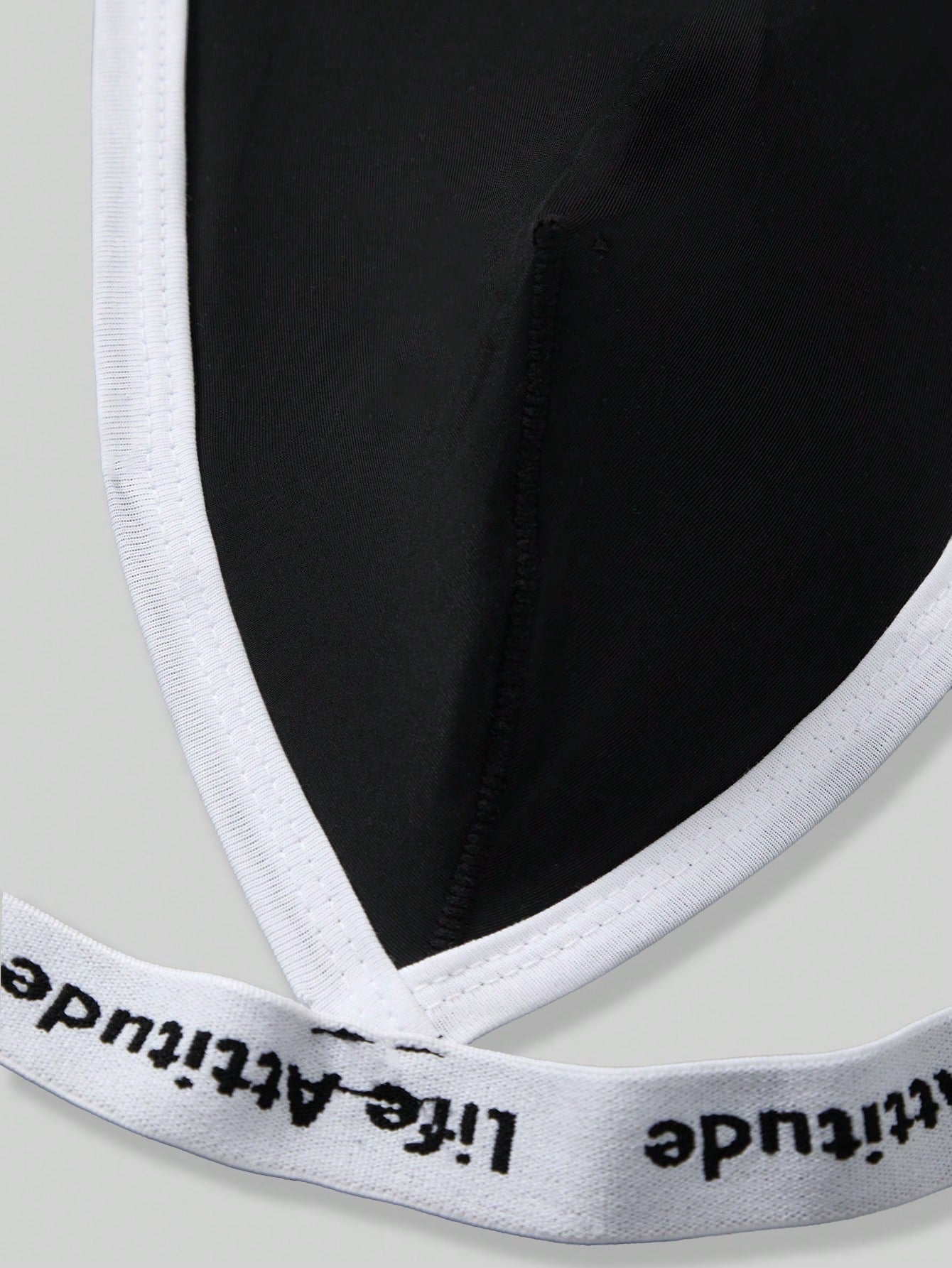 Men's black low rise thong underwear in knitted fabric with letter and striped pattern, medium stretch, made from polyamide and elastane.