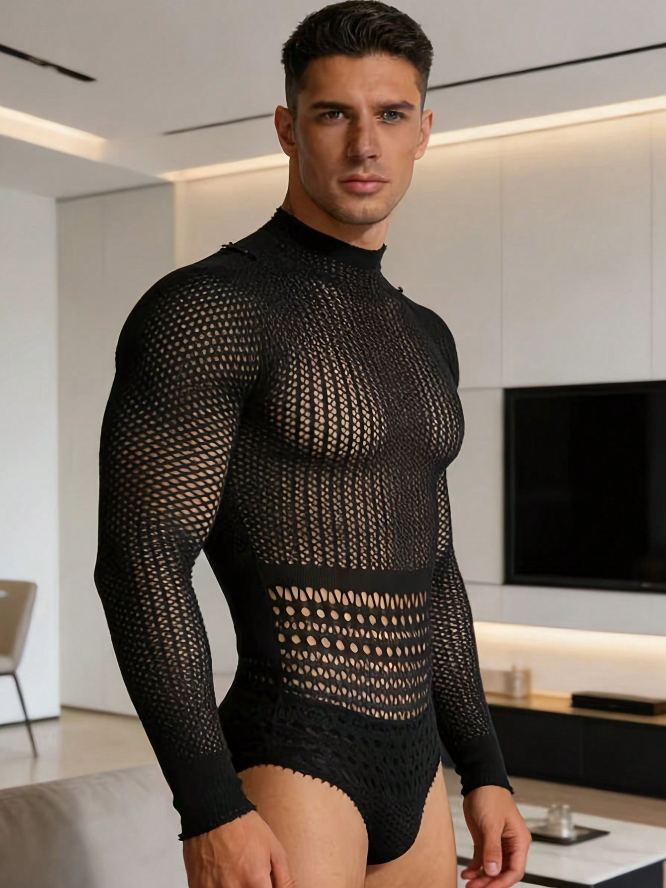Black fishnet jumpsuit lingerie for men with hollow out detail, sheer knitted fabric, stand collar, high rise fit, and high stretch polyamide construction.