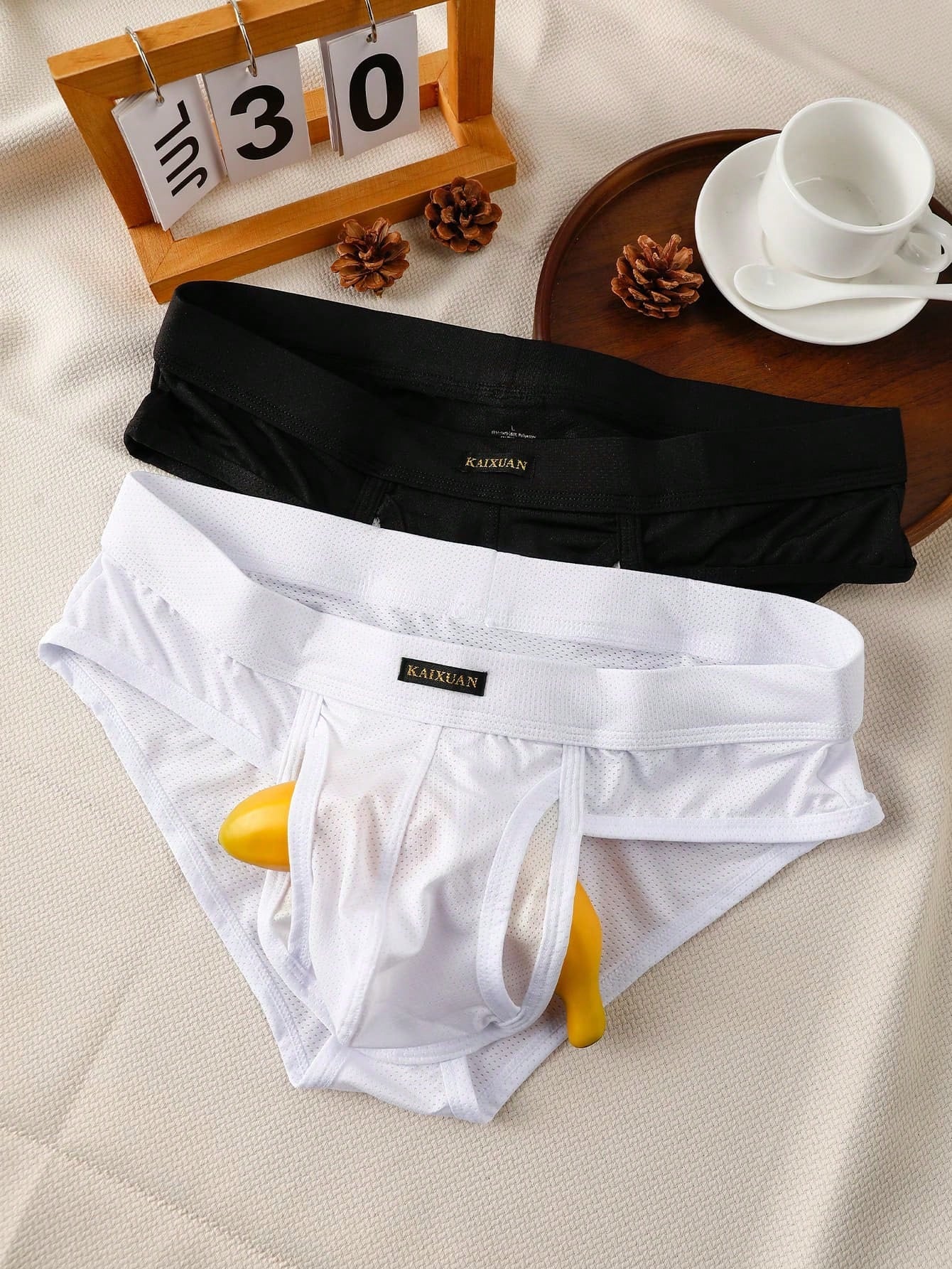 Men's low rise mesh briefs with letter graphic pattern, multicolor design, patched detail, zipper accent, and medium stretch polyester elastane fabric.