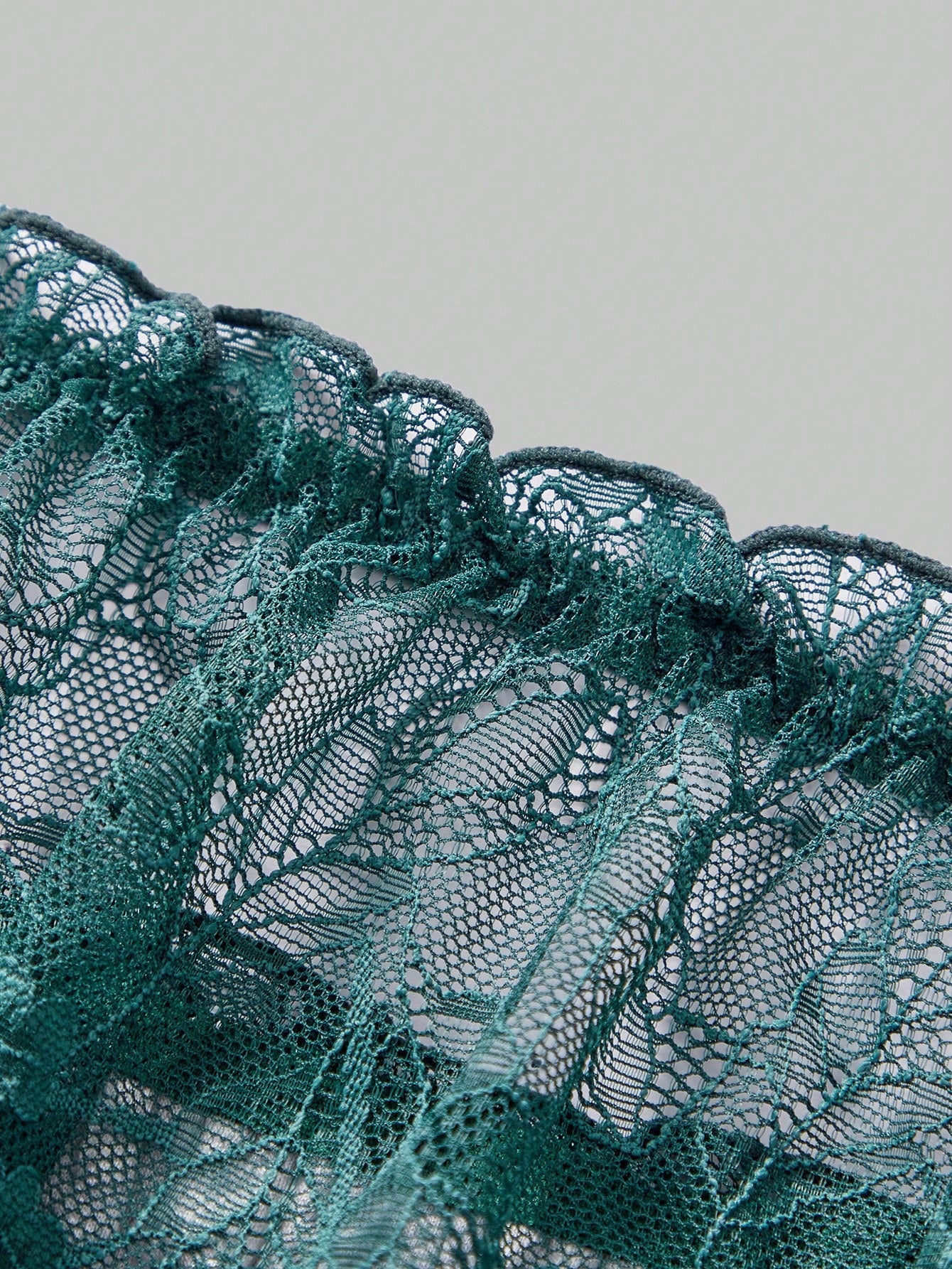 Dark green men's lace thong underwear with semi-sheer contrast lace, low-rise fit, and knitted stretch fabric.