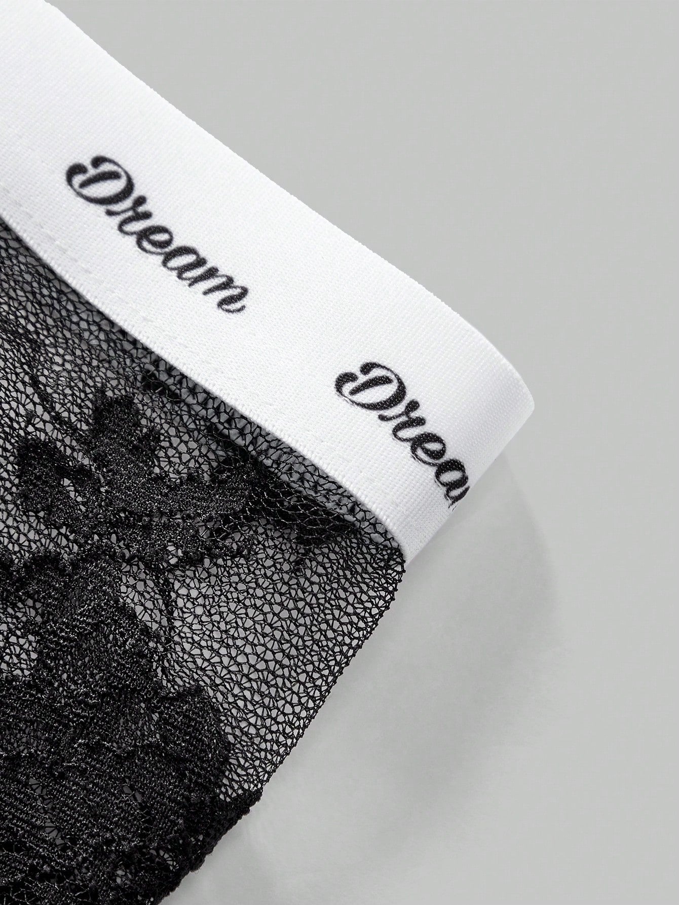 Men's black and white lace trim briefs with letter and plant pattern, regular fit, slight stretch, made from polyamide and elastane.
