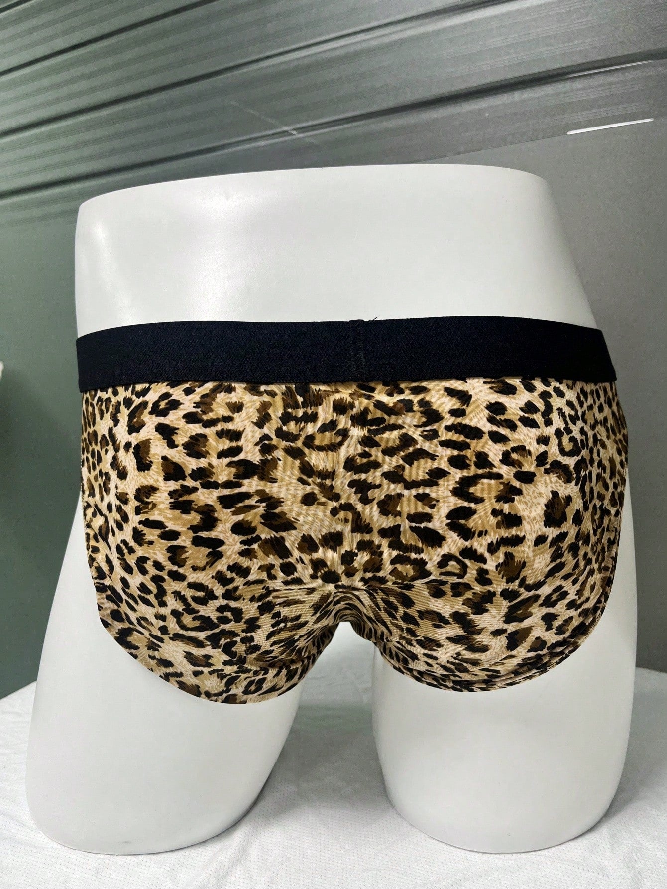 Men's khaki mid rise briefs with a textured leopard-inspired pattern, backless design, contrast binding, and medium-stretch polyester elastane fabric.