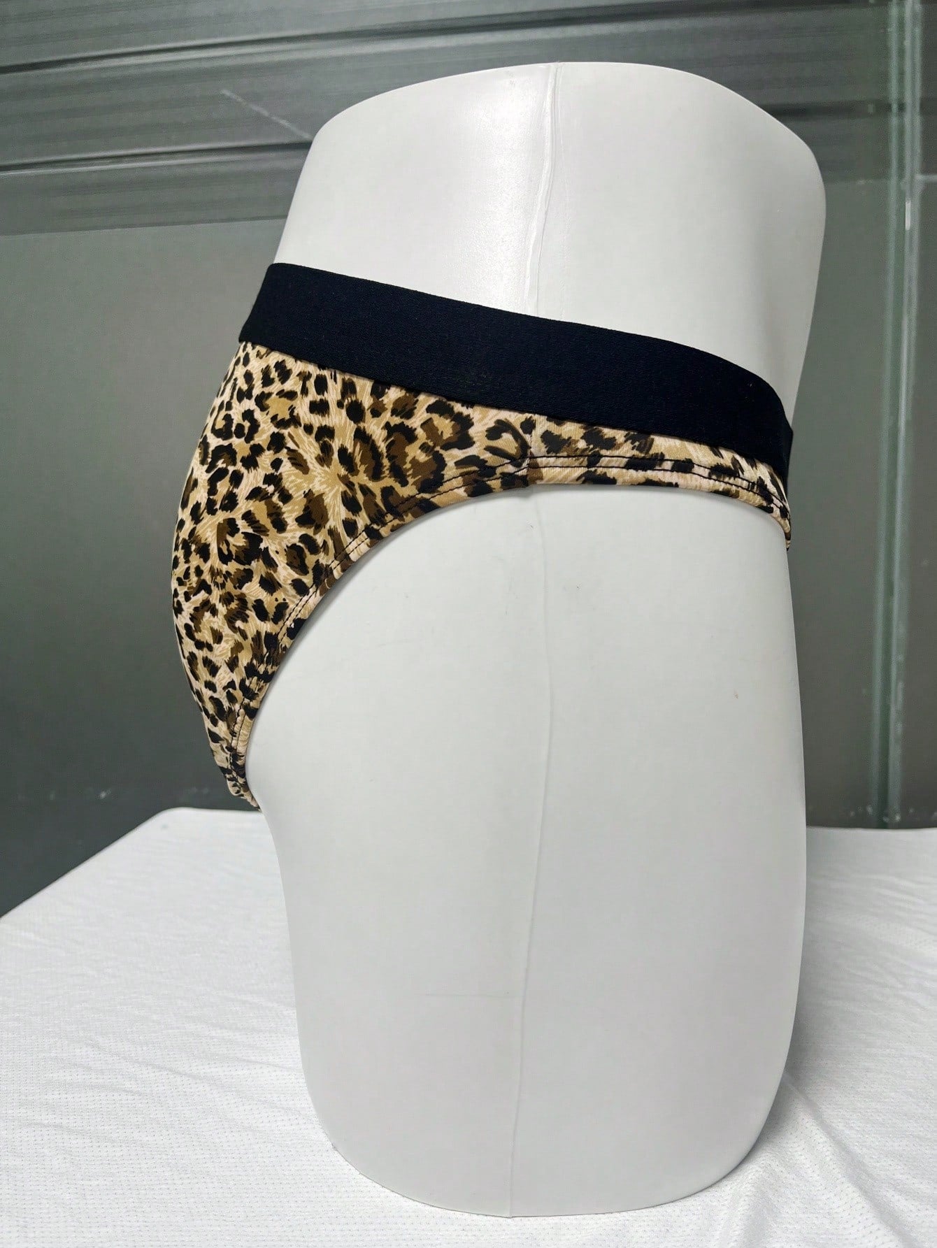 Men's khaki mid rise briefs with a textured leopard-inspired pattern, backless design, contrast binding, and medium-stretch polyester elastane fabric.