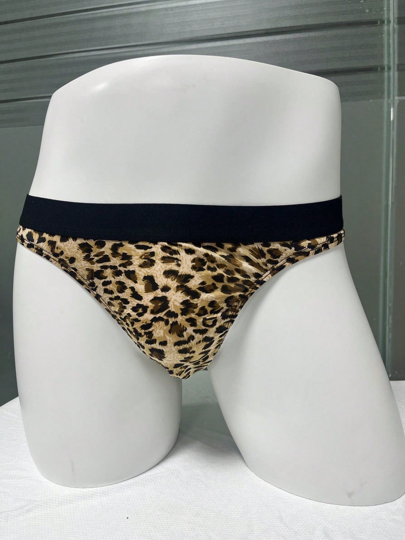 Men's khaki mid rise briefs with a textured leopard-inspired pattern, backless design, contrast binding, and medium-stretch polyester elastane fabric.