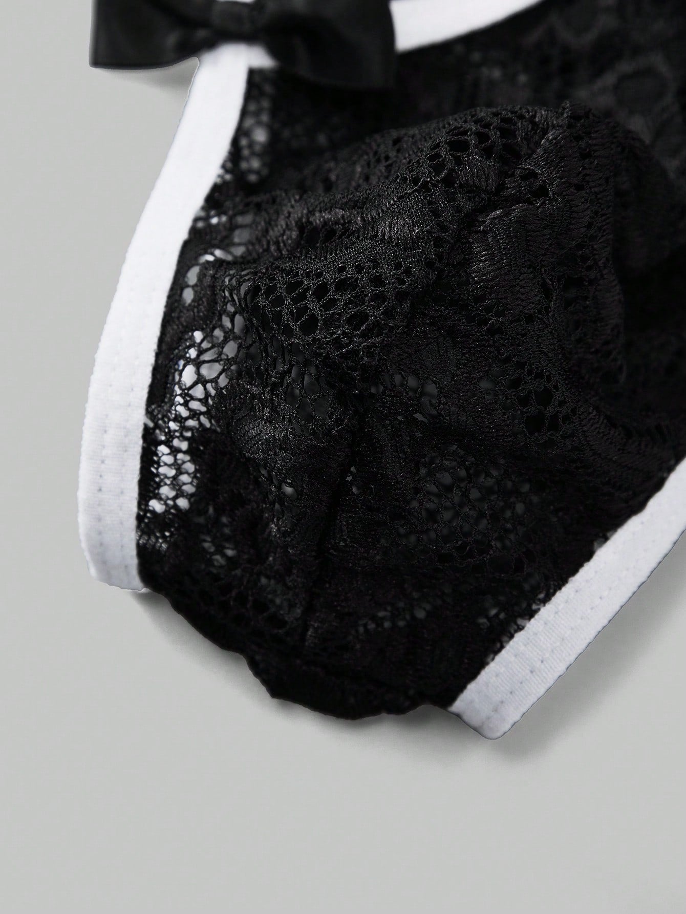 Men's black semi-sheer lace thong underwear with low rise fit, plain pattern, slight stretch fabric, and bowknot ribbon detail.