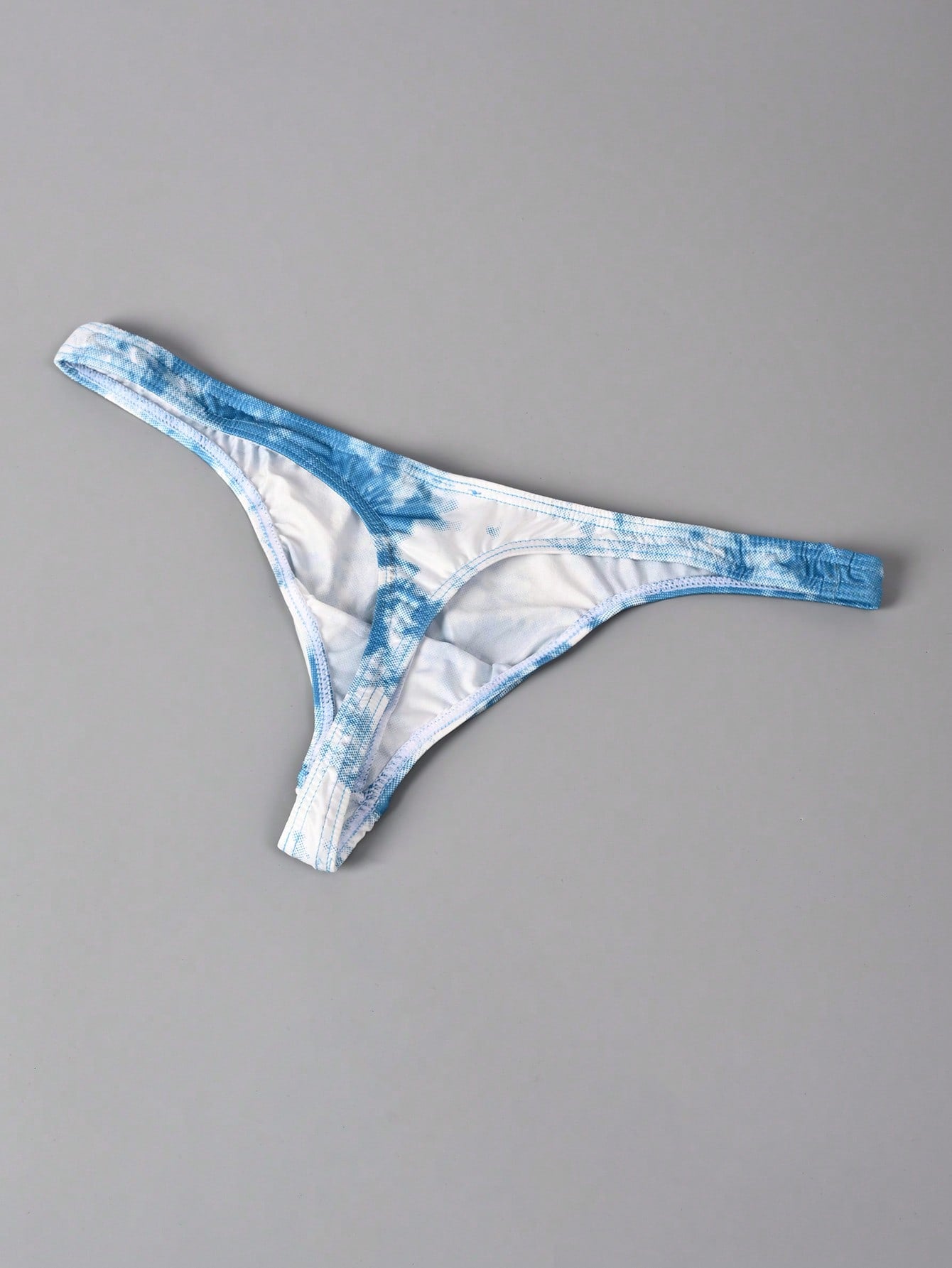 Men's tie dye thong underwear with a low rise fit and T-back design, made from polyester and elastane stretch fabric.