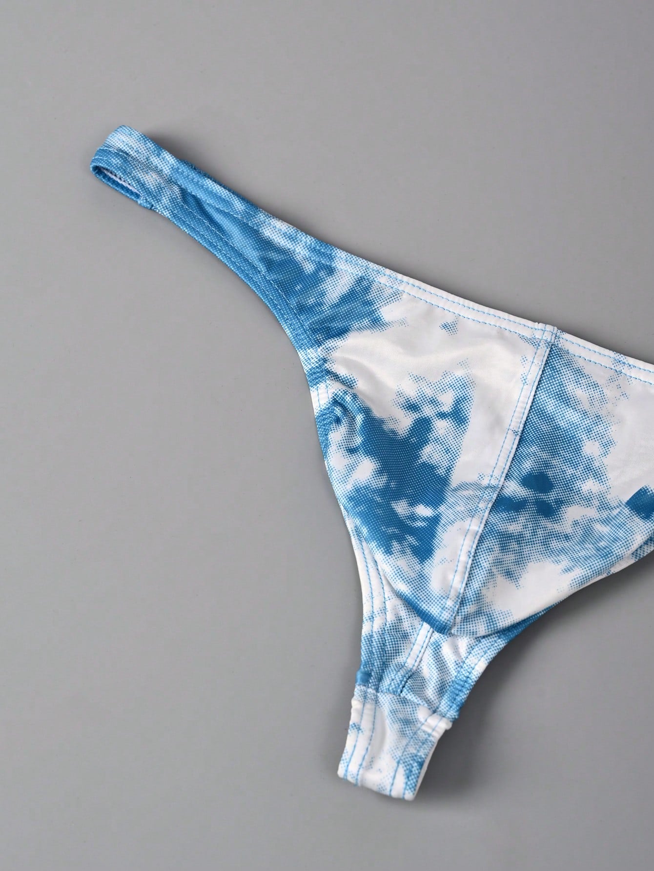 Men's tie dye thong underwear with a low rise fit and T-back design, made from polyester and elastane stretch fabric.