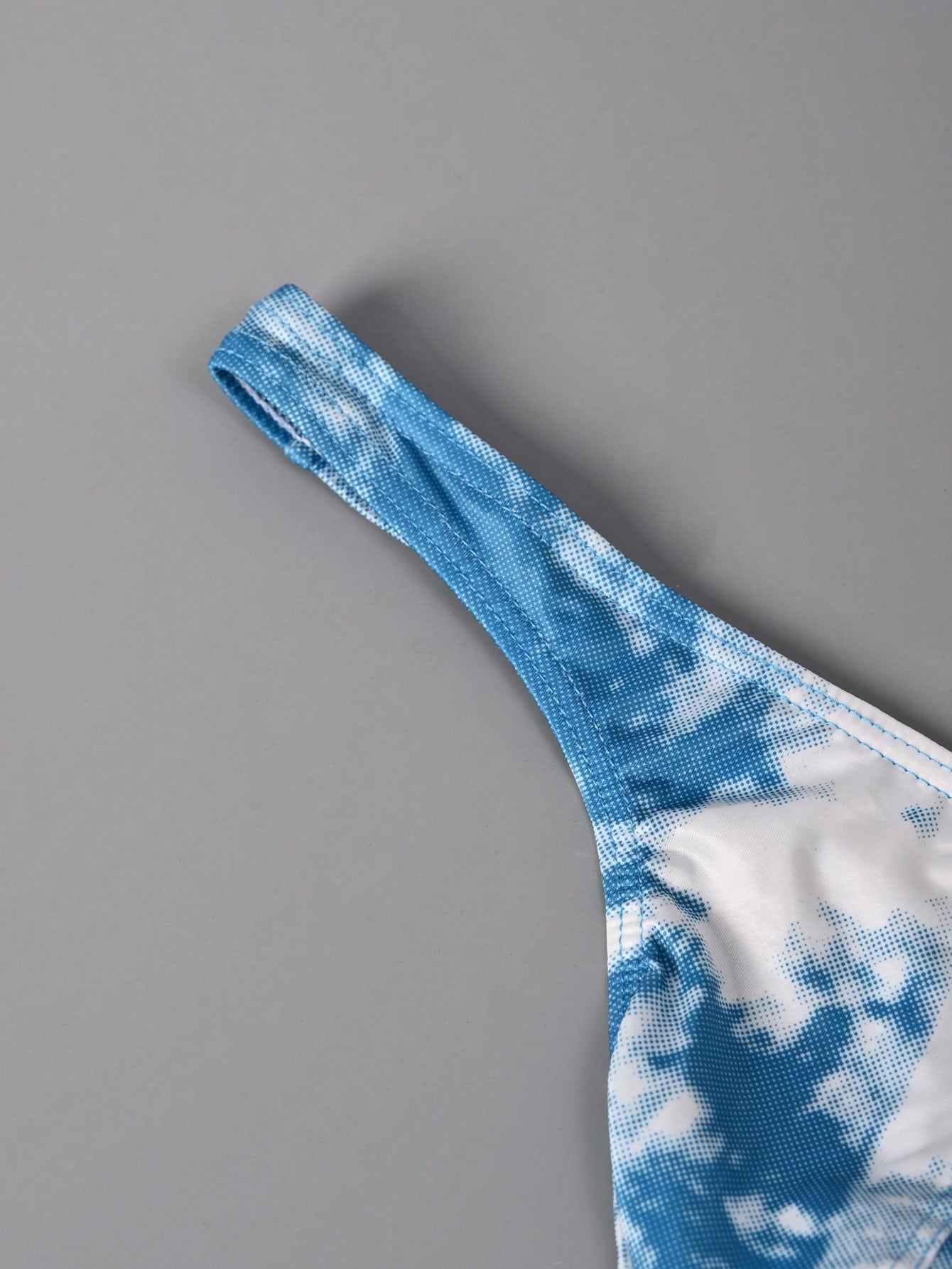 Men's tie dye thong underwear with a low rise fit and T-back design, made from polyester and elastane stretch fabric.