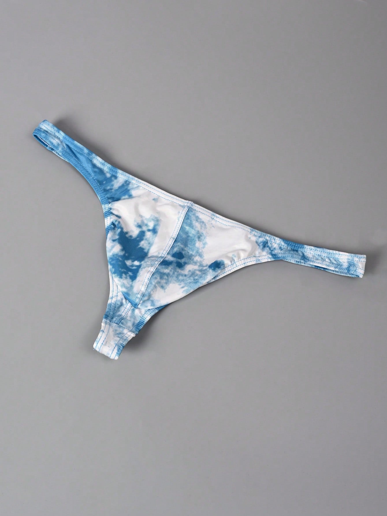 Men's tie dye thong underwear with a low rise fit and T-back design, made from polyester and elastane stretch fabric.