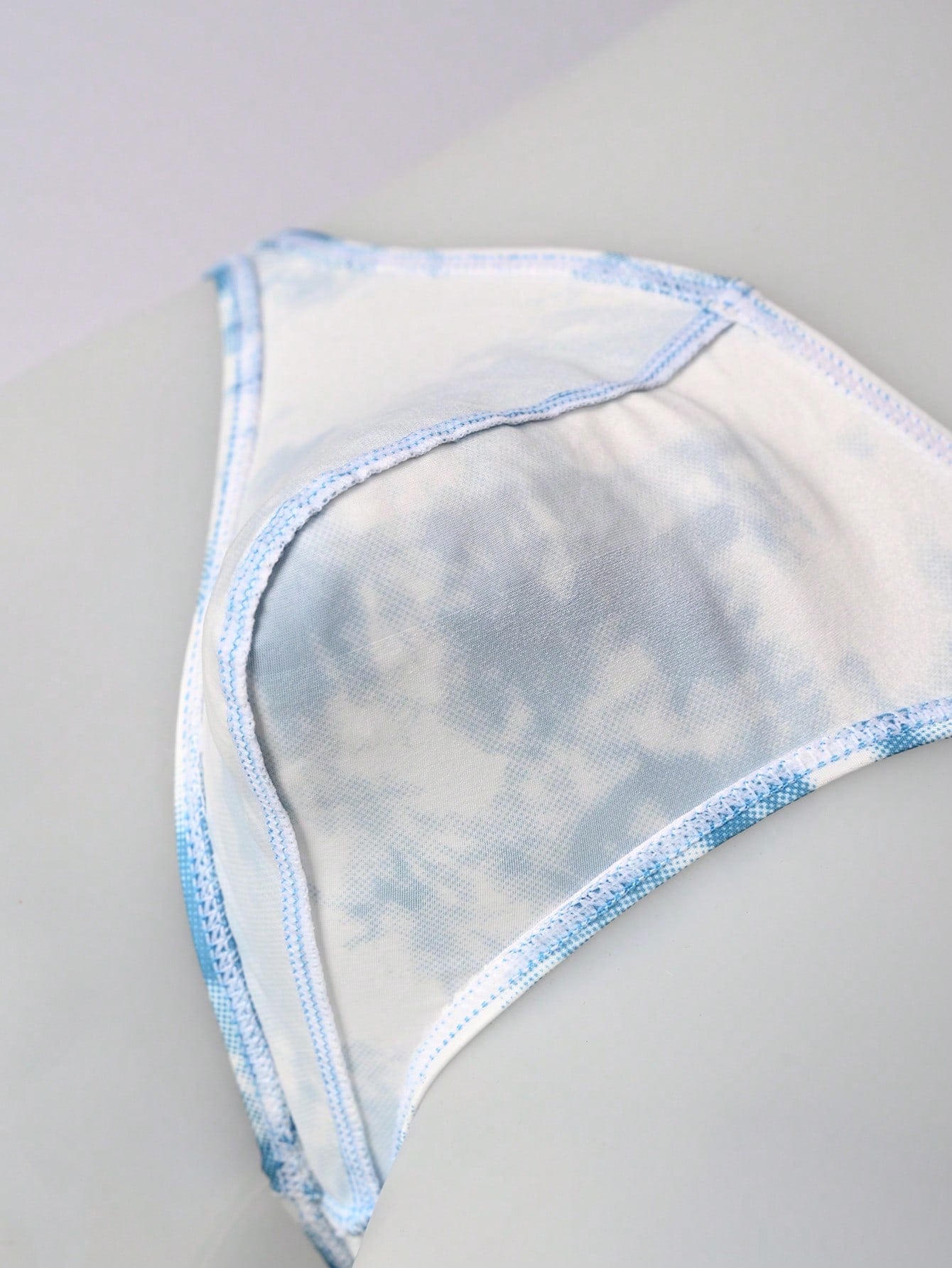Men's tie dye thong underwear with a low rise fit and T-back design, made from polyester and elastane stretch fabric.