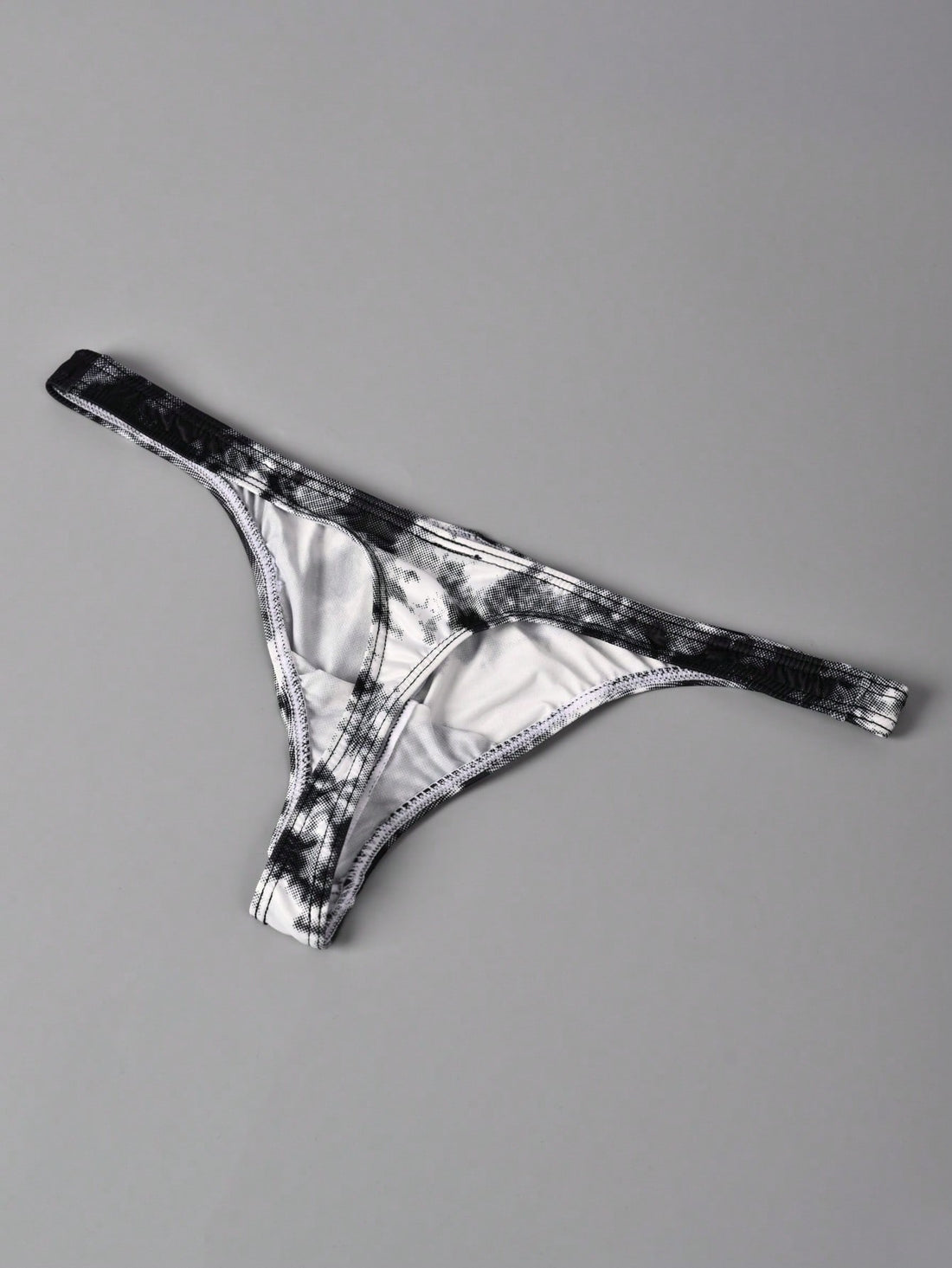 Men's tie dye thong underwear with a low rise fit and T-back design, made from polyester and elastane stretch fabric.