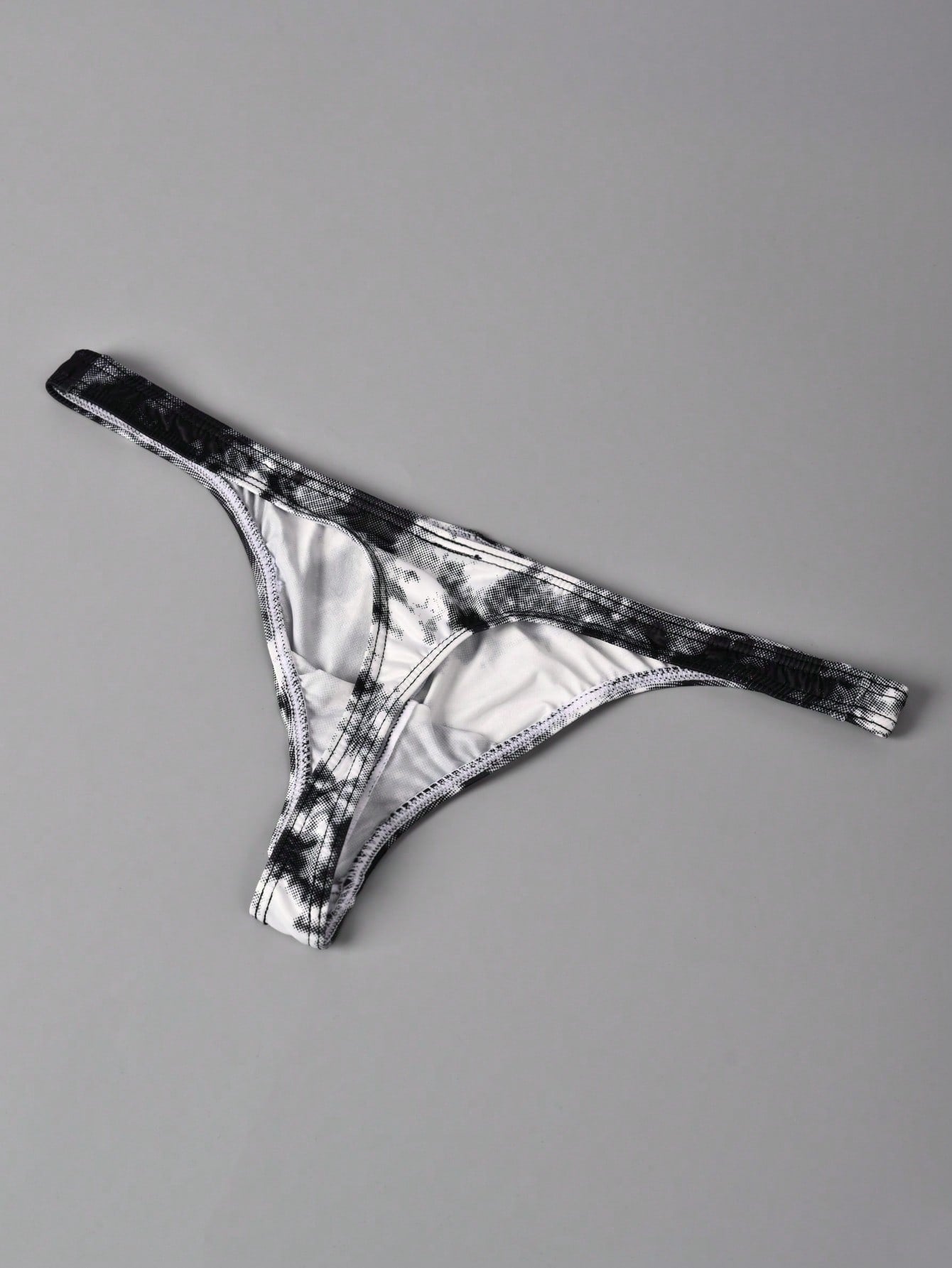 Men's tie dye thong underwear with a low rise fit and T-back design, made from polyester and elastane stretch fabric.
