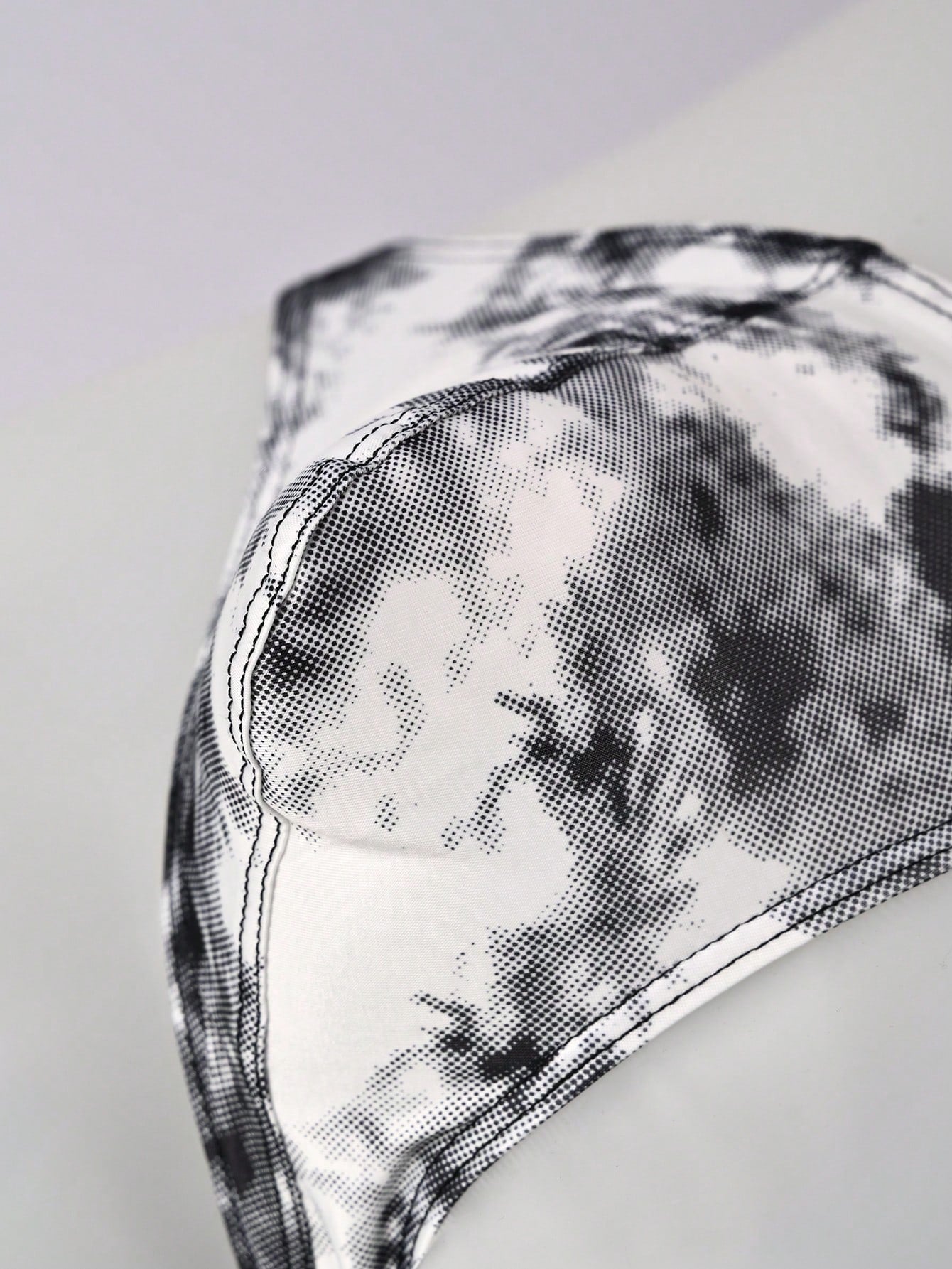 Men's tie dye thong underwear with a low rise fit and T-back design, made from polyester and elastane stretch fabric.