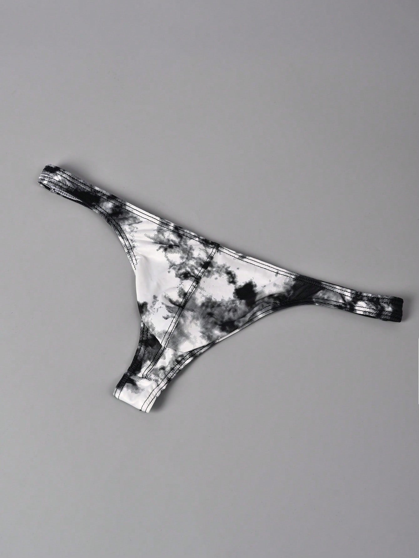 Men's tie dye thong underwear with a low rise fit and T-back design, made from polyester and elastane stretch fabric.