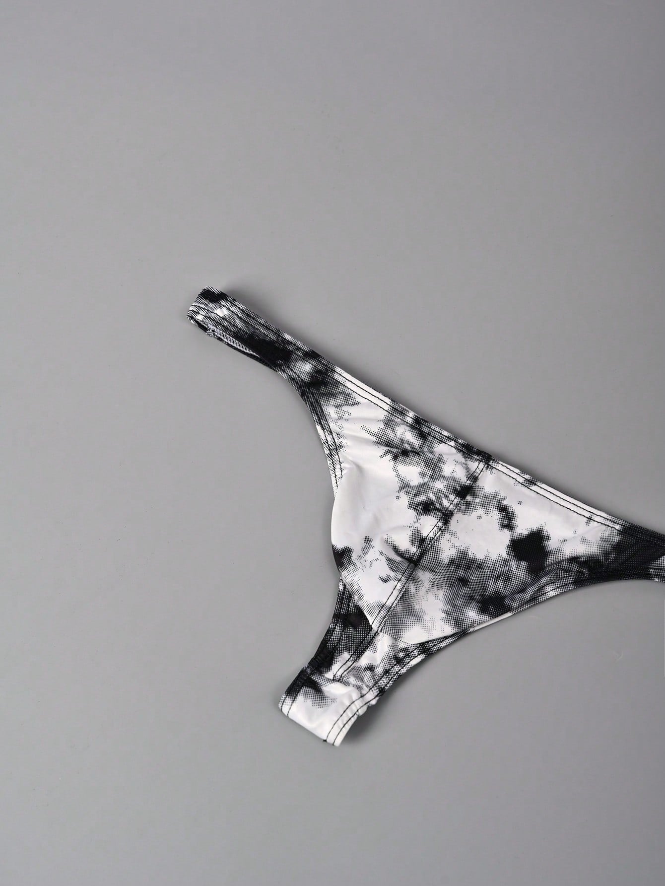 Men's tie dye thong underwear with a low rise fit and T-back design, made from polyester and elastane stretch fabric.