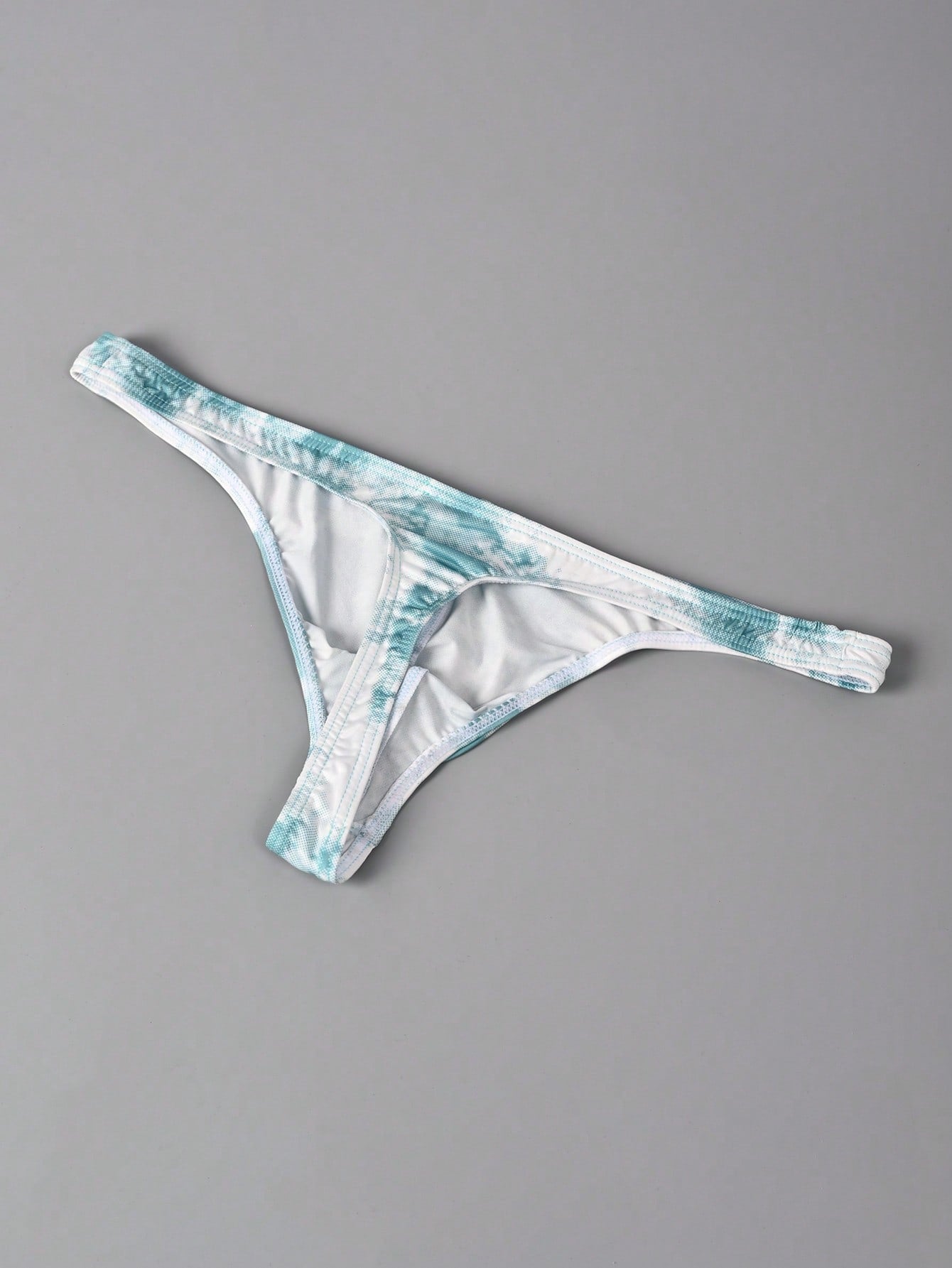 Men's tie dye thong underwear with a low rise fit and T-back design, made from polyester and elastane stretch fabric.