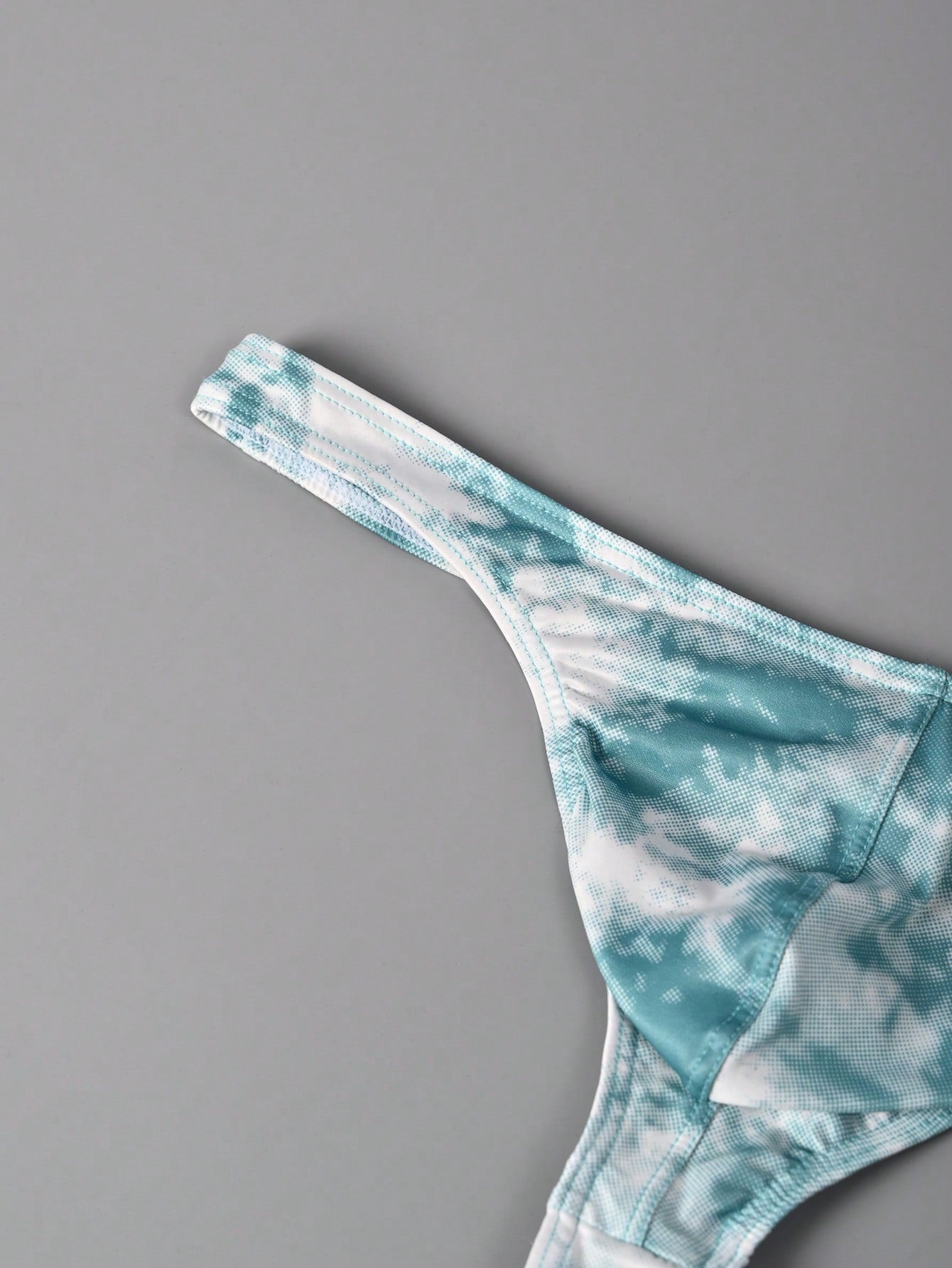Men's tie dye thong underwear with a low rise fit and T-back design, made from polyester and elastane stretch fabric.